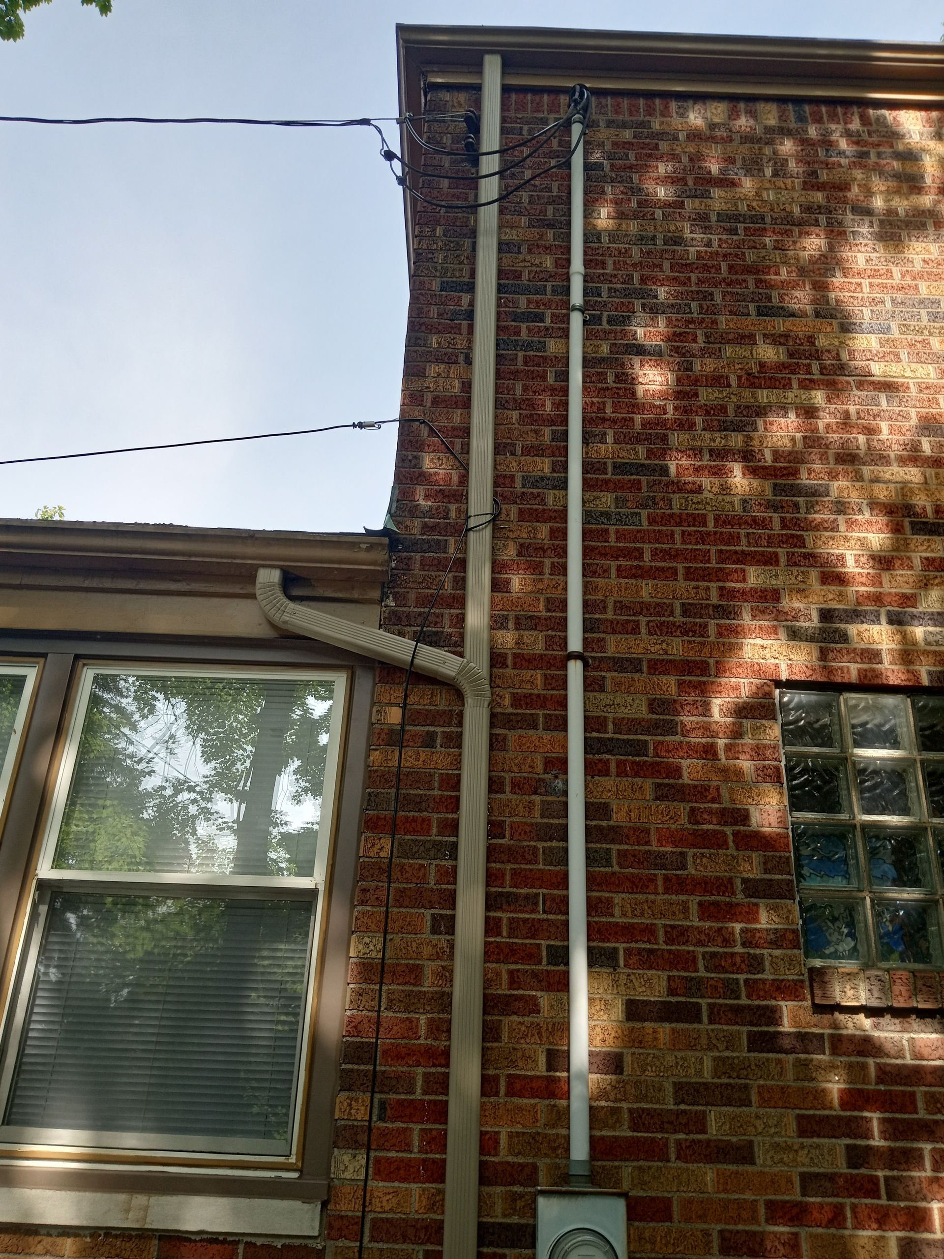 Tan metal-sided building with dark green trim and roof against a cloudy sky.