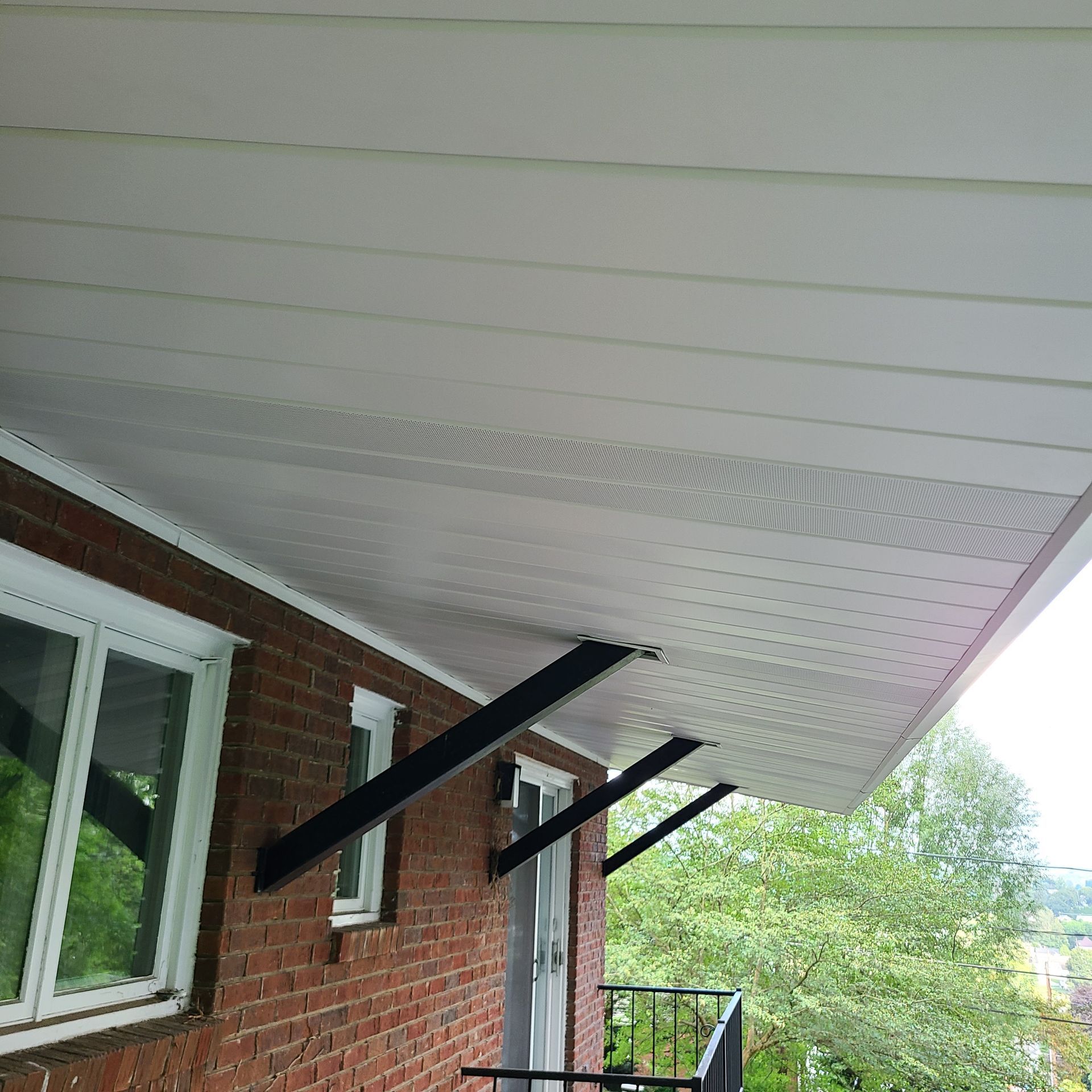 White awning supported by black metal brackets on a brick building.