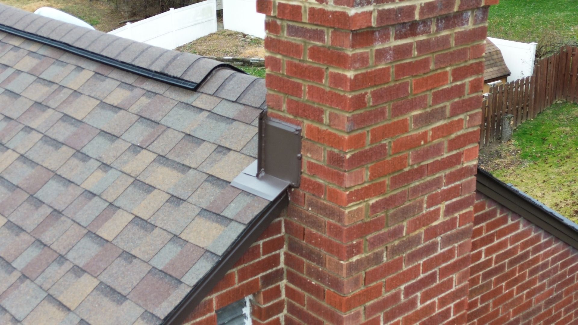 Brick chimney on a shingle roof with flashing.