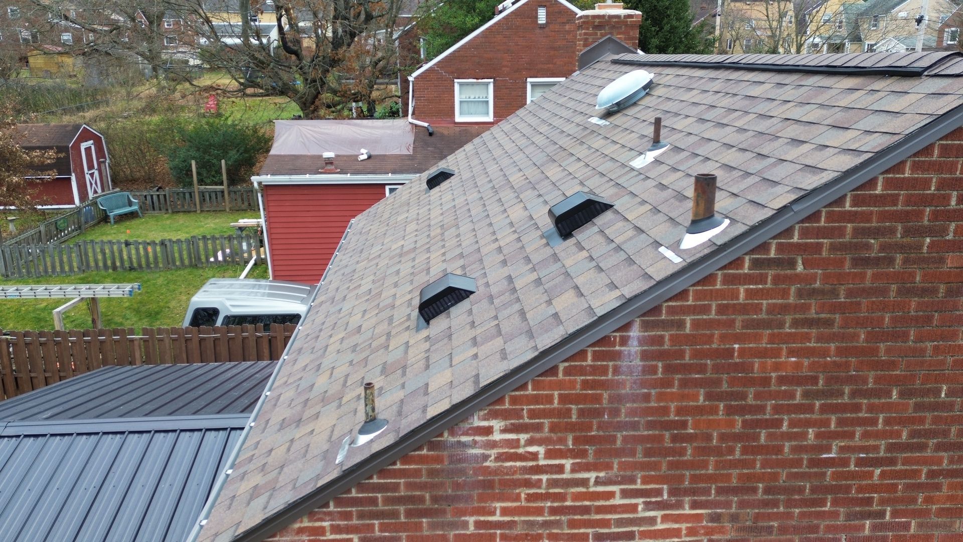 Brick chimney with dark metal flashing on a gray asphalt shingle roof.