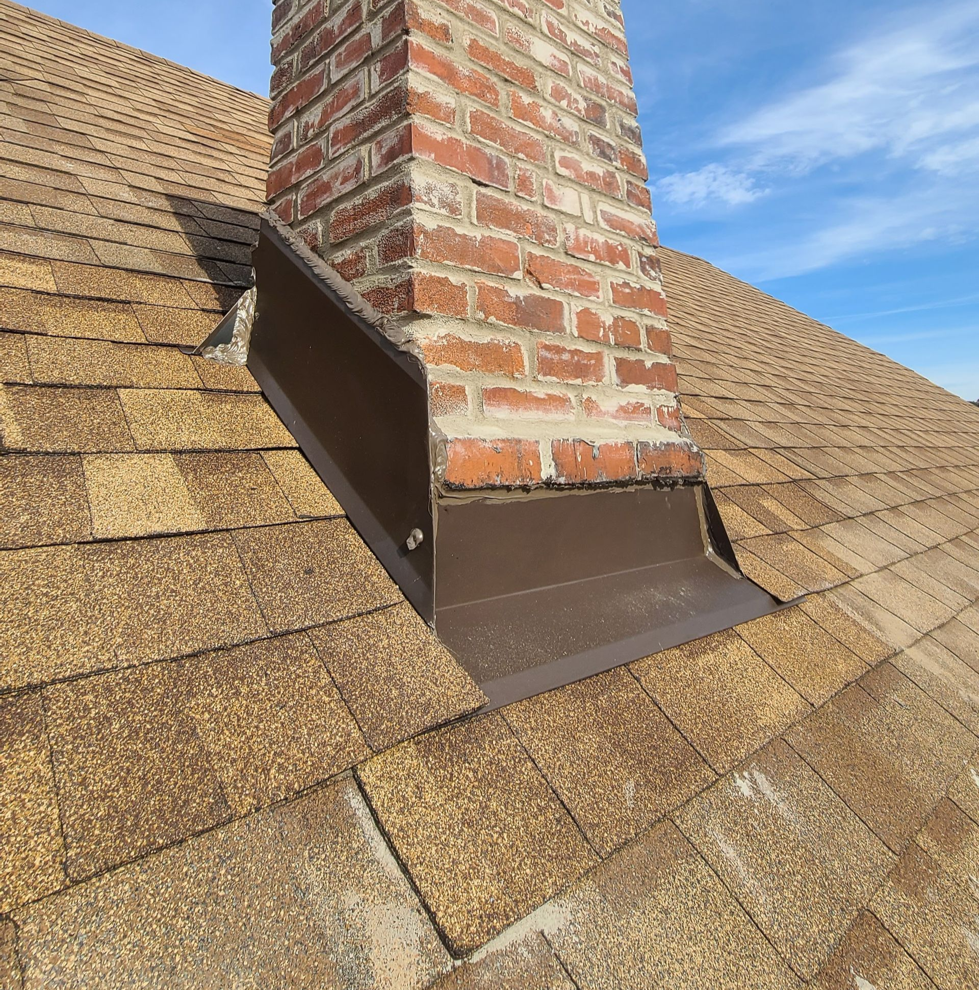 Roofing work in progress; gray shingles, dark underlayment, tools visible, residential setting.