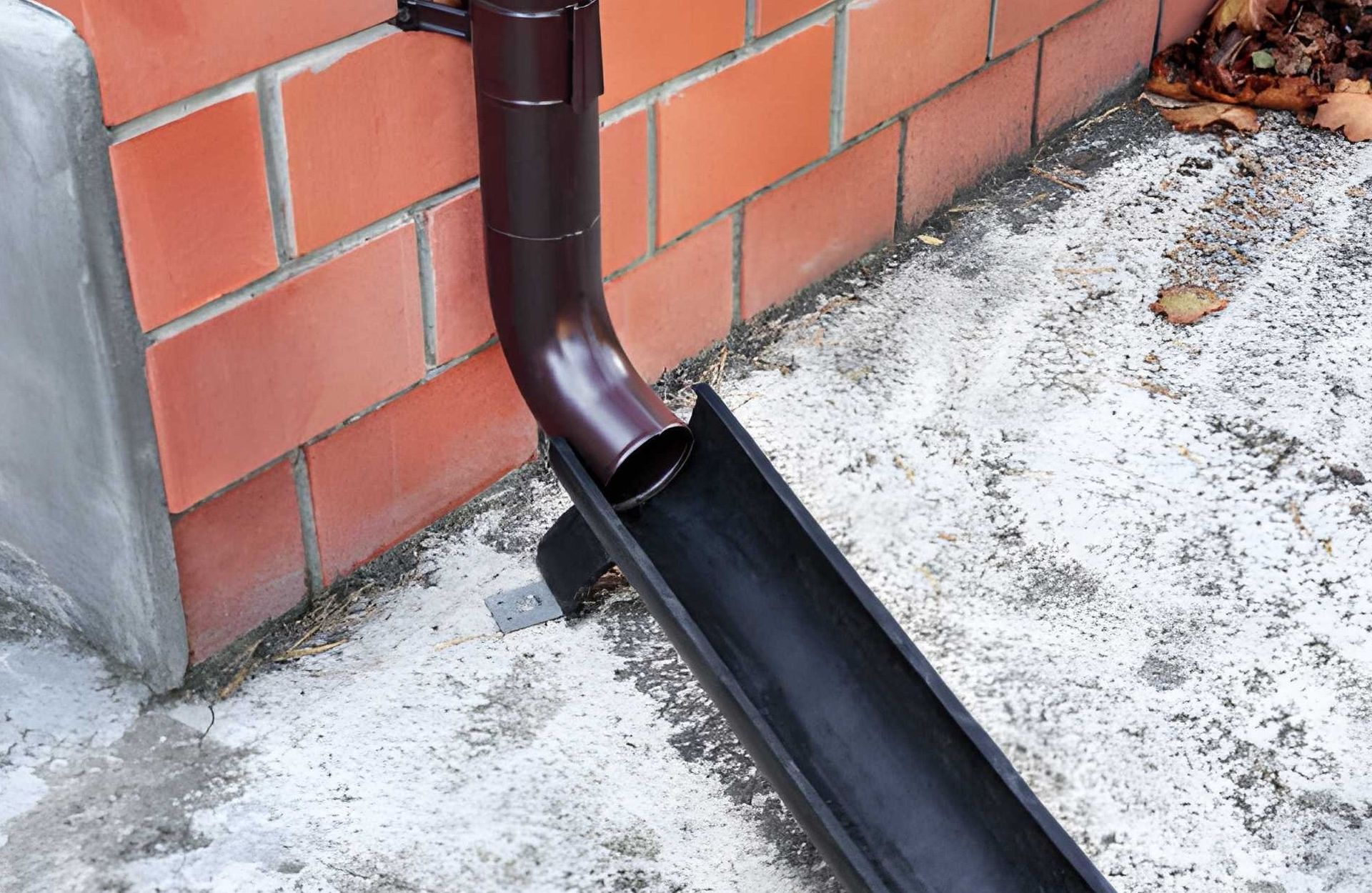 Silver rain gutters and downspouts on a green building with blue sky background.