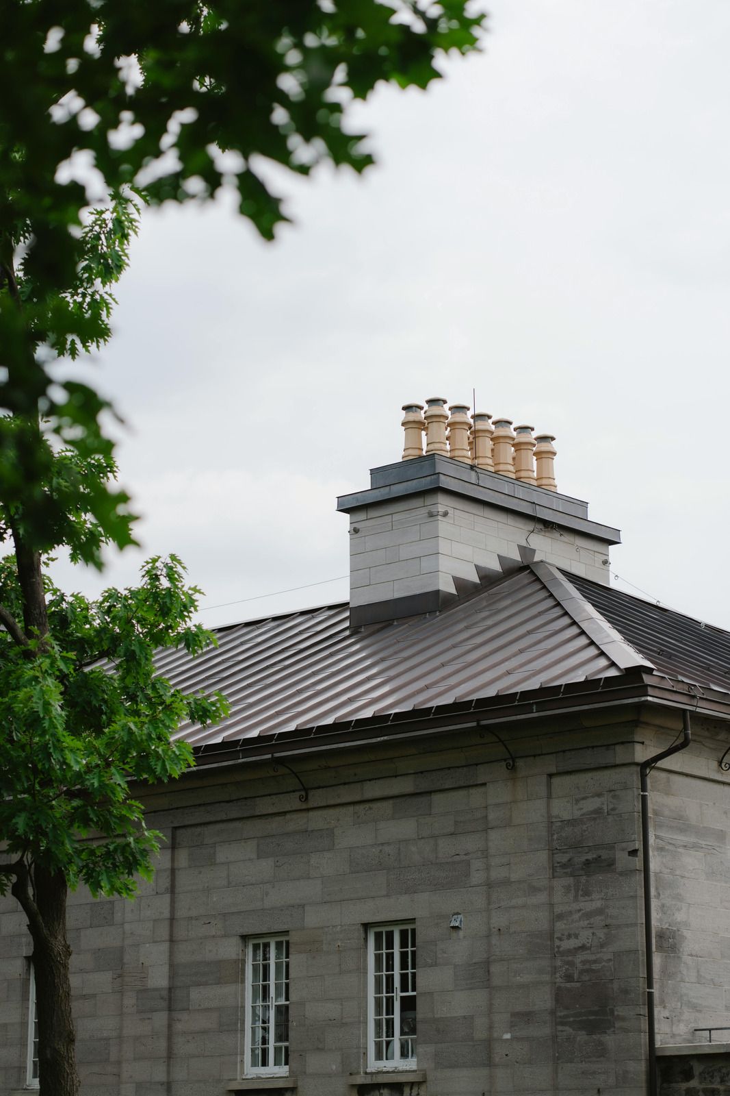 Roofer in gloves installing copper gutter on a wooden shingle roof in a natural setting.