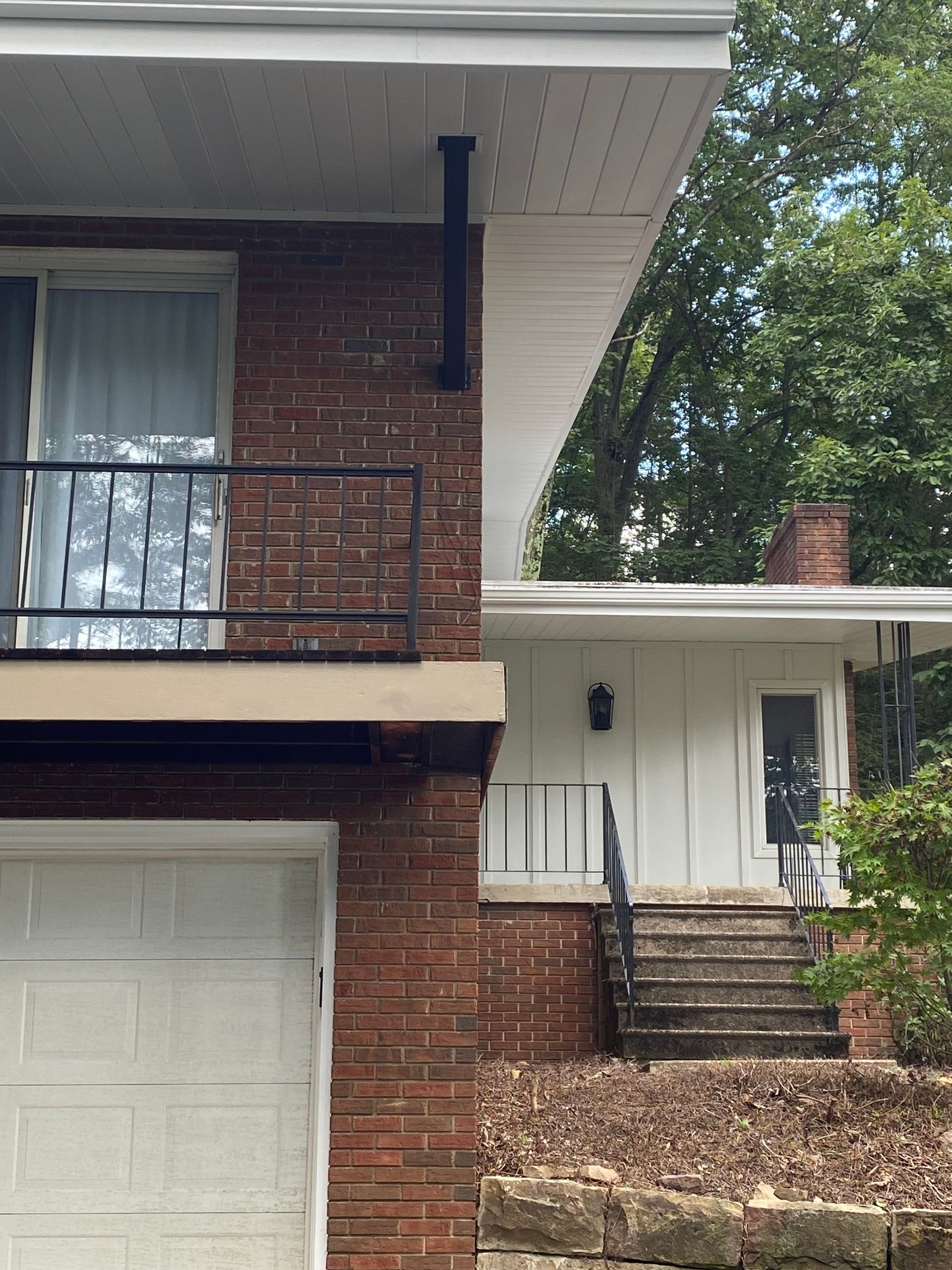 Exterior of a brick home with a balcony, garage, and front entrance with steps.
