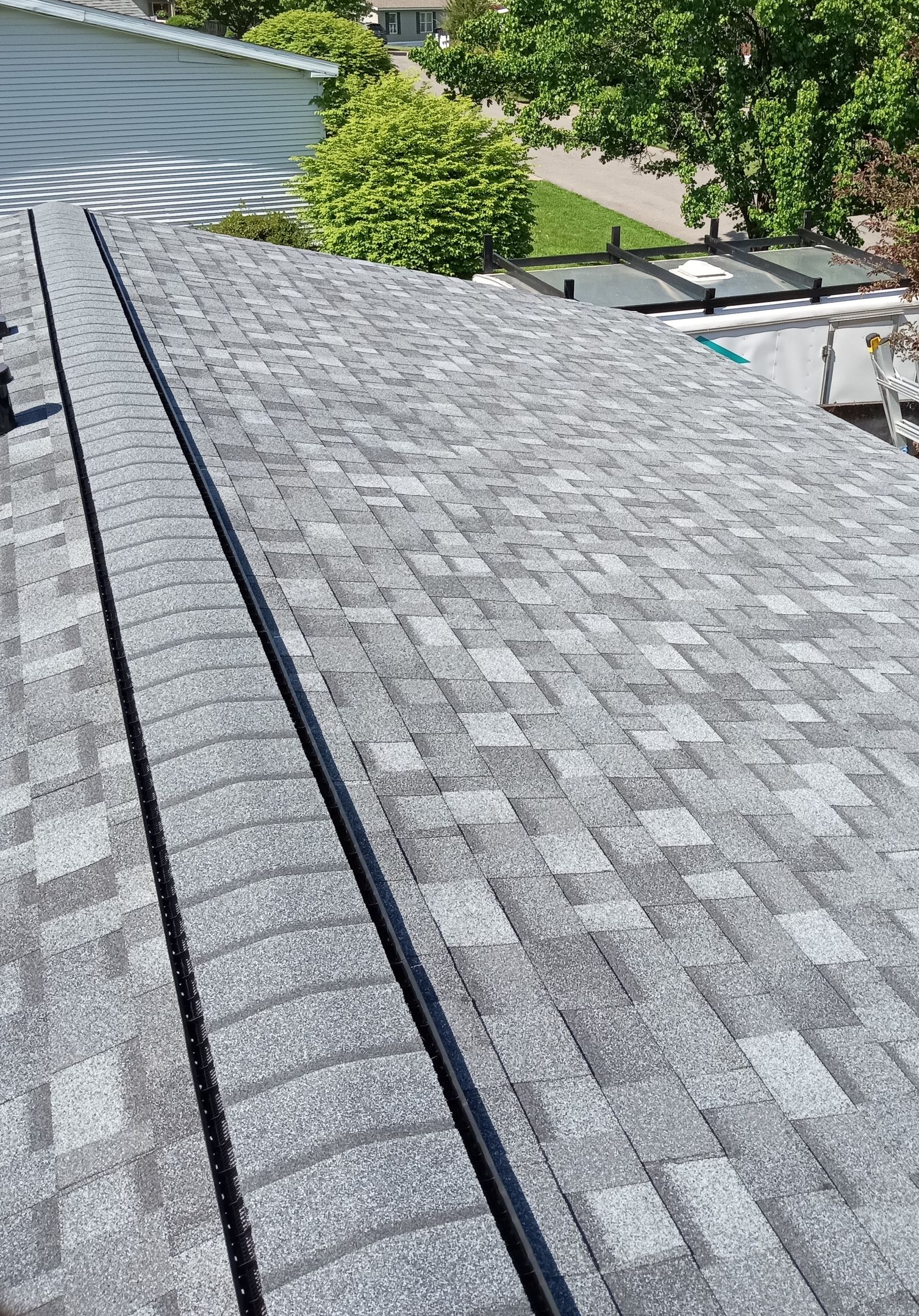 Gray asphalt shingle roof with a black metal valley in the middle.