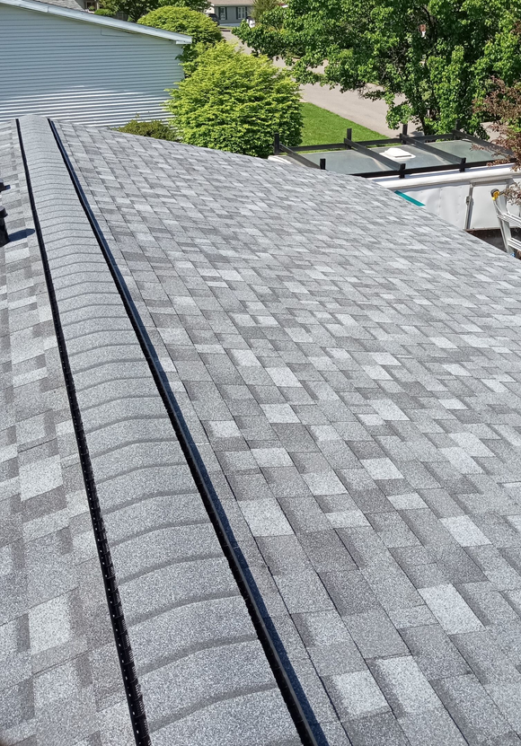 Gray asphalt shingle roof with a black metal valley in the middle.