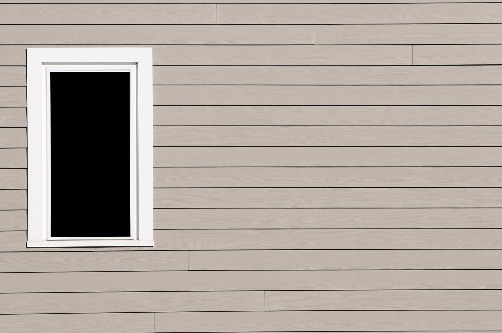 Window with white trim in a beige, horizontal-planked wall.