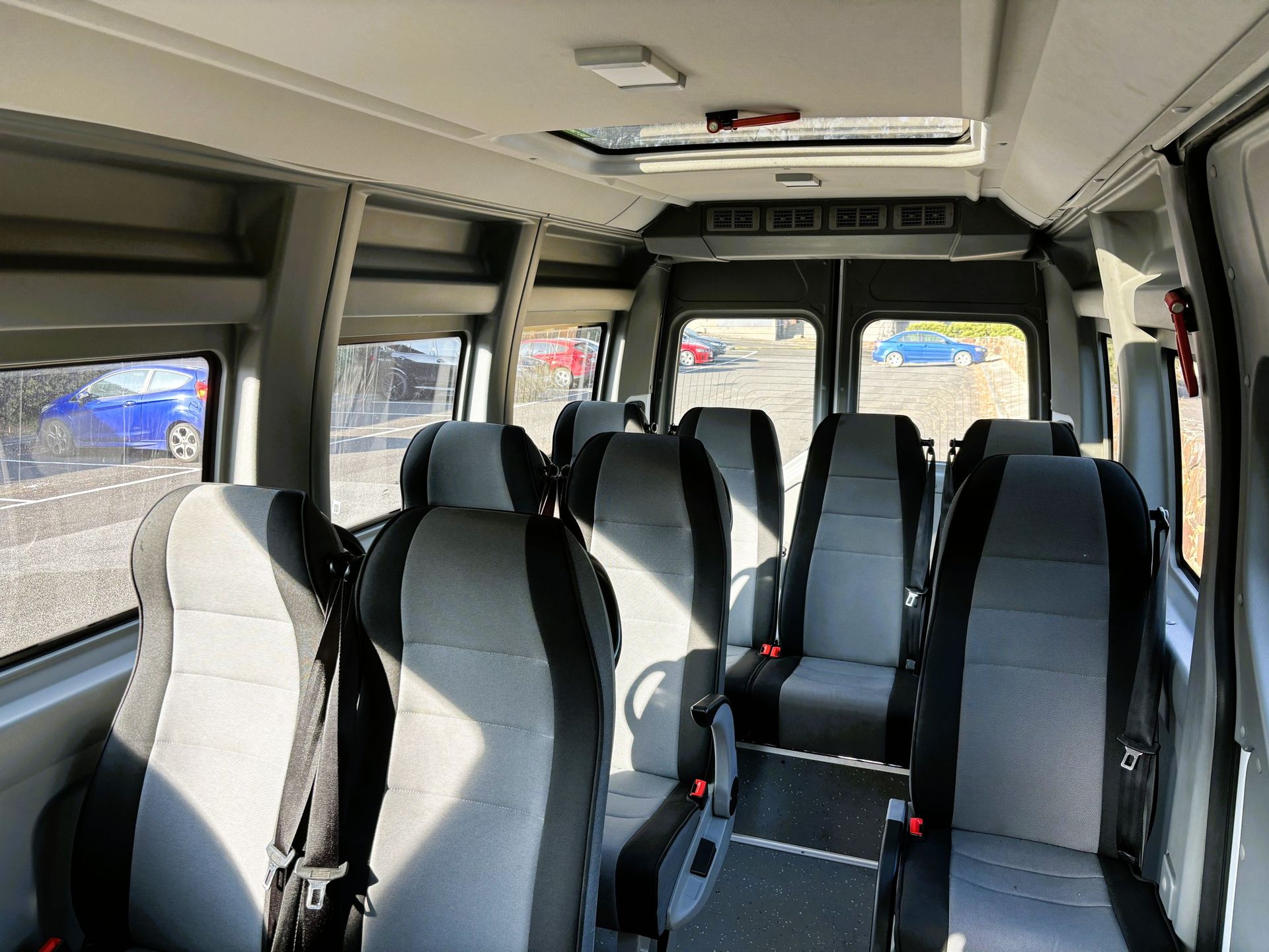 An inside photo of a Ticket 2 Ride minibus with sun shining through the spacious windows.