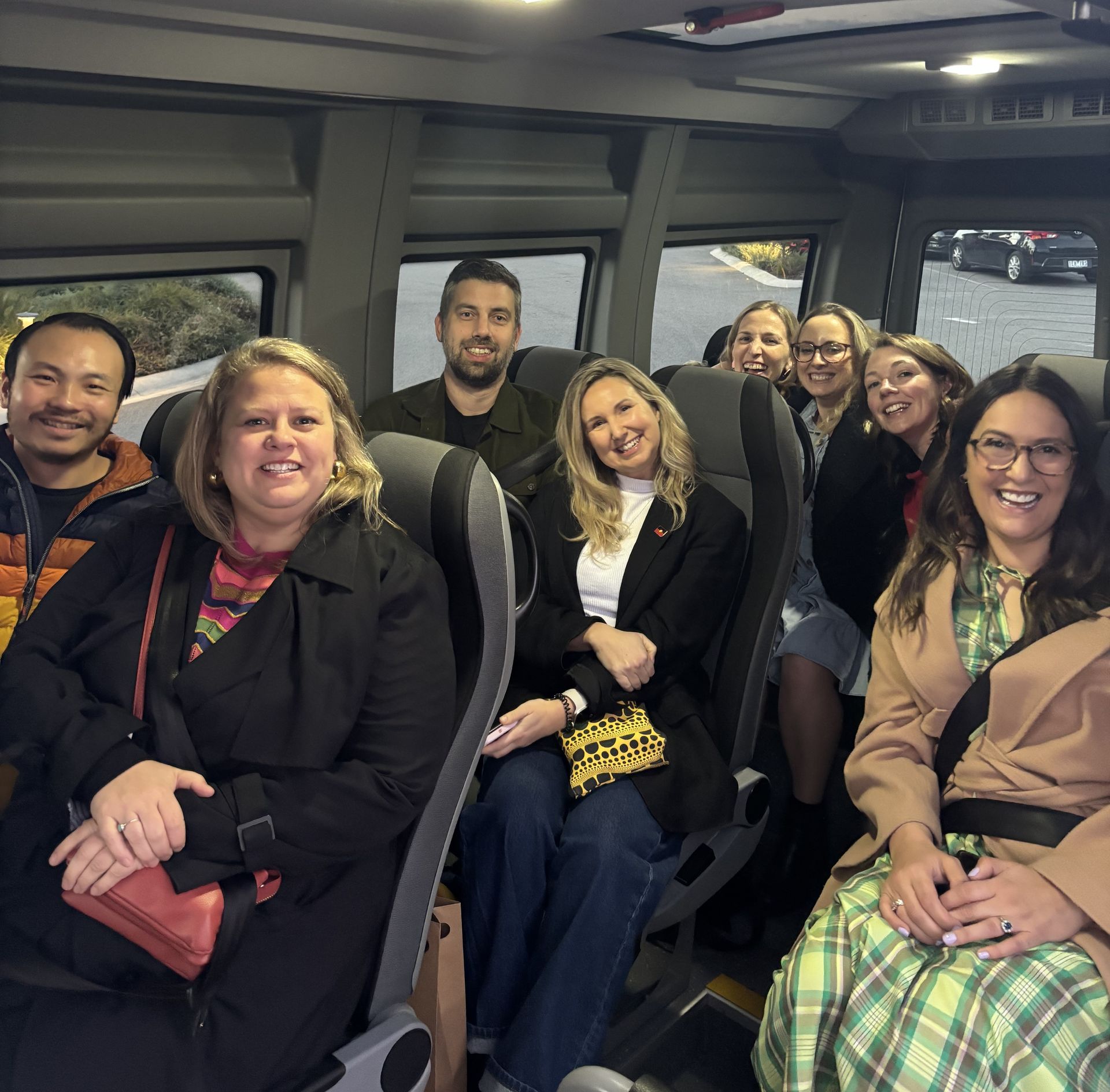 A group of passengers, smiling and enjoying their winery tour.