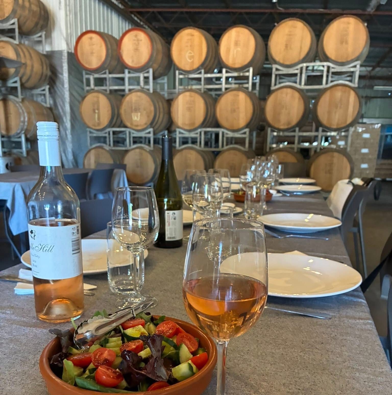 A photo of inside a winery with barrels stacked three rows high.