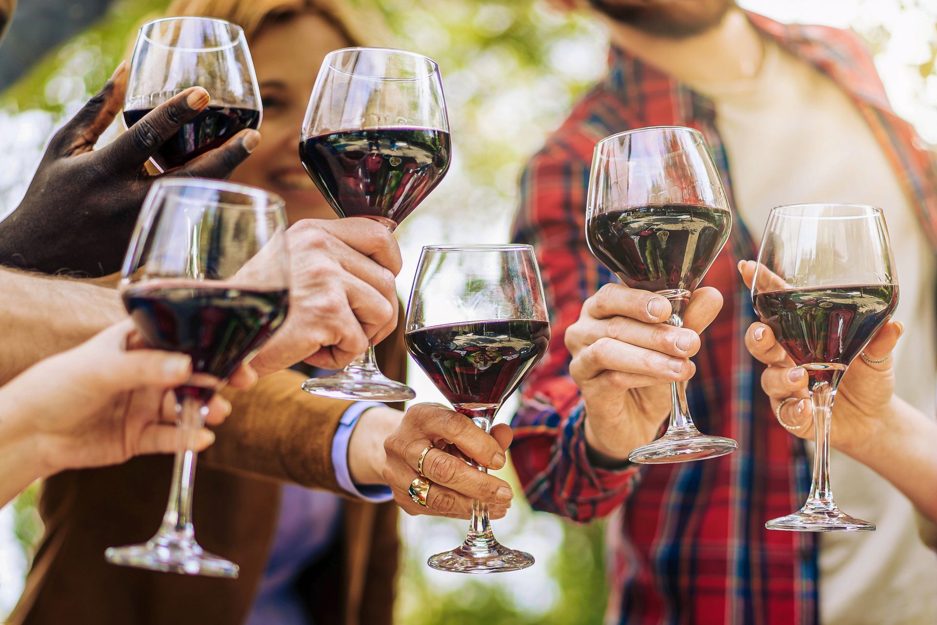 A close up photo of wine glasses with winery tour passengers outdoors.