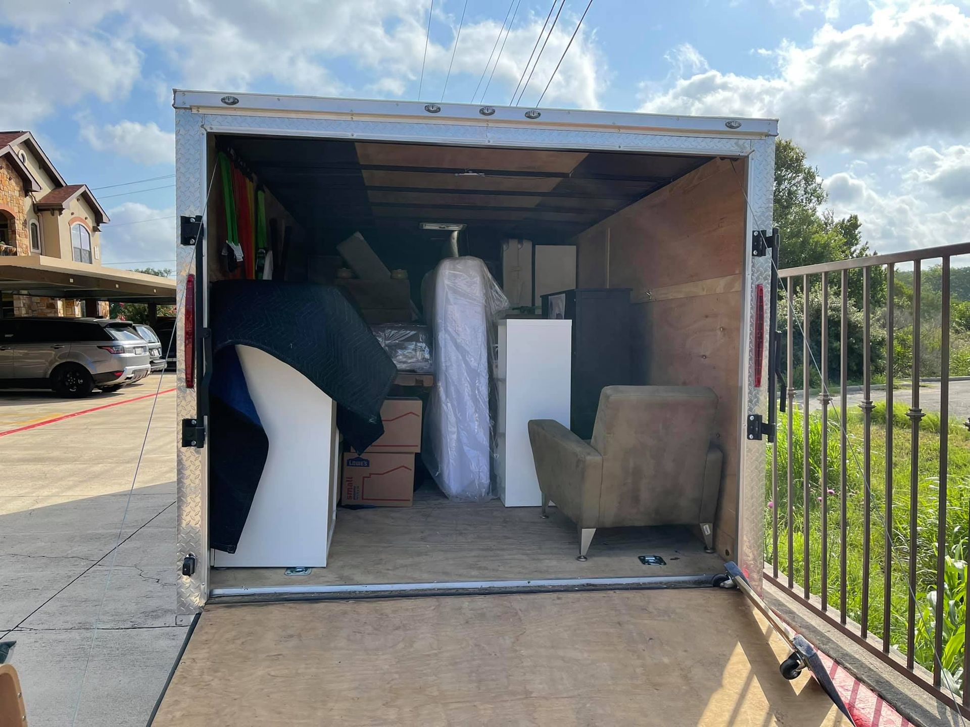 The inside of a trailer filled with furniture and a mattress.