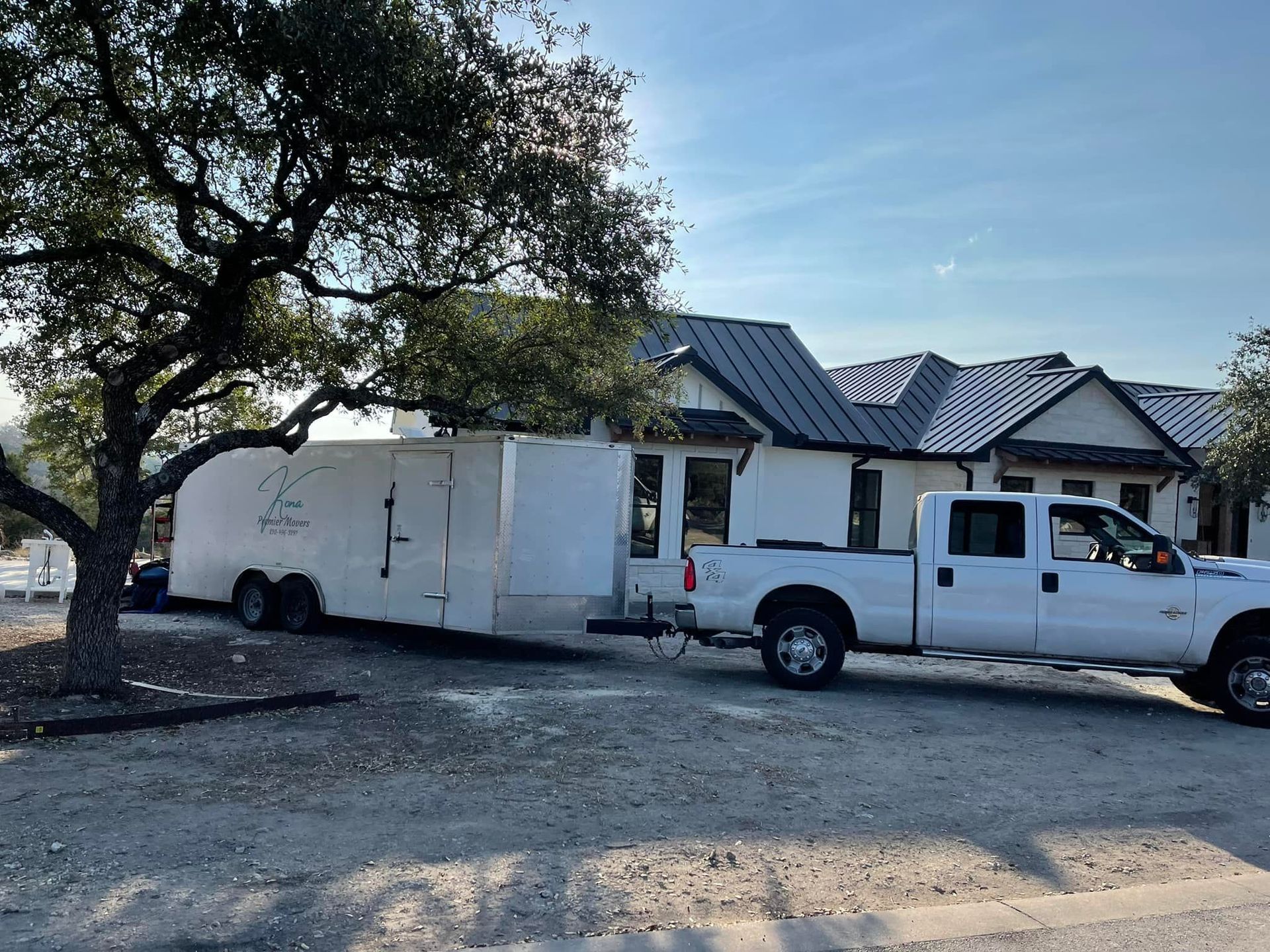 A white truck with a trailer attached to it is parked in front of a house.