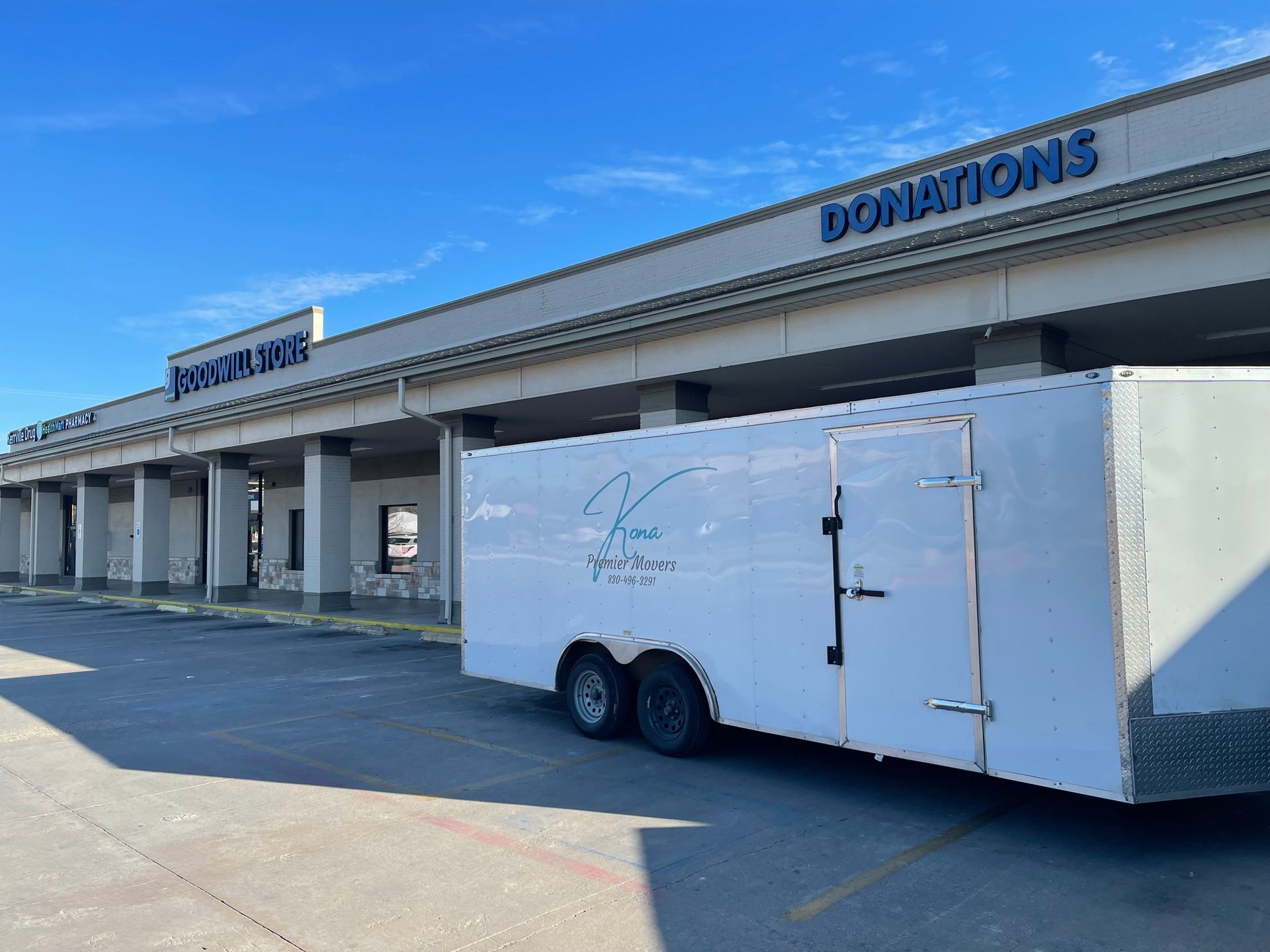 A white trailer is parked in front of a building that says donations.