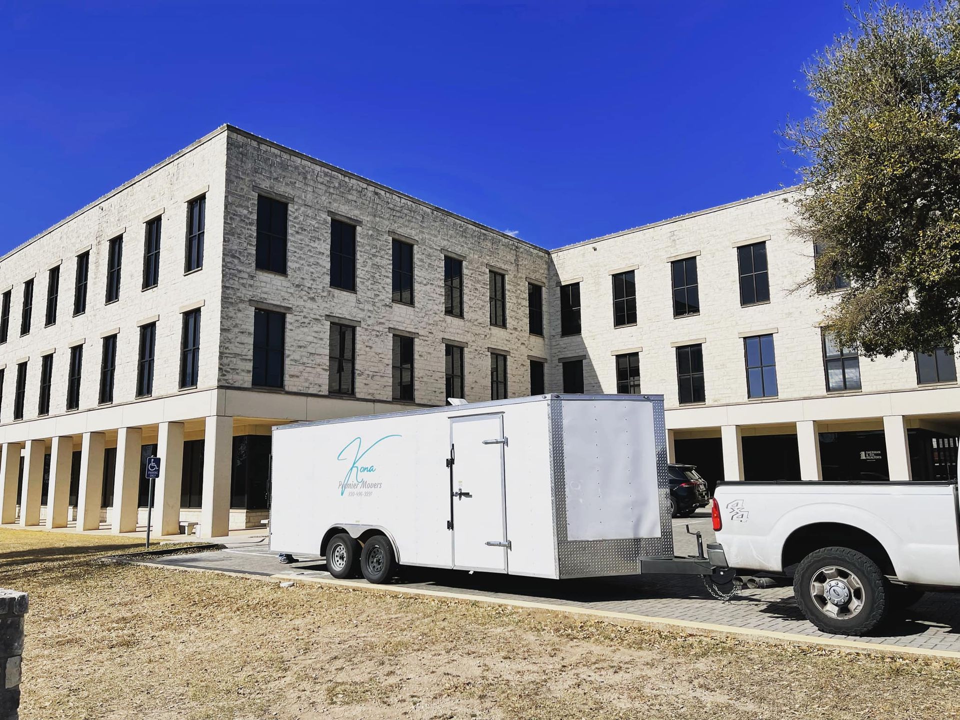 A white trailer is parked in front of a large building.
