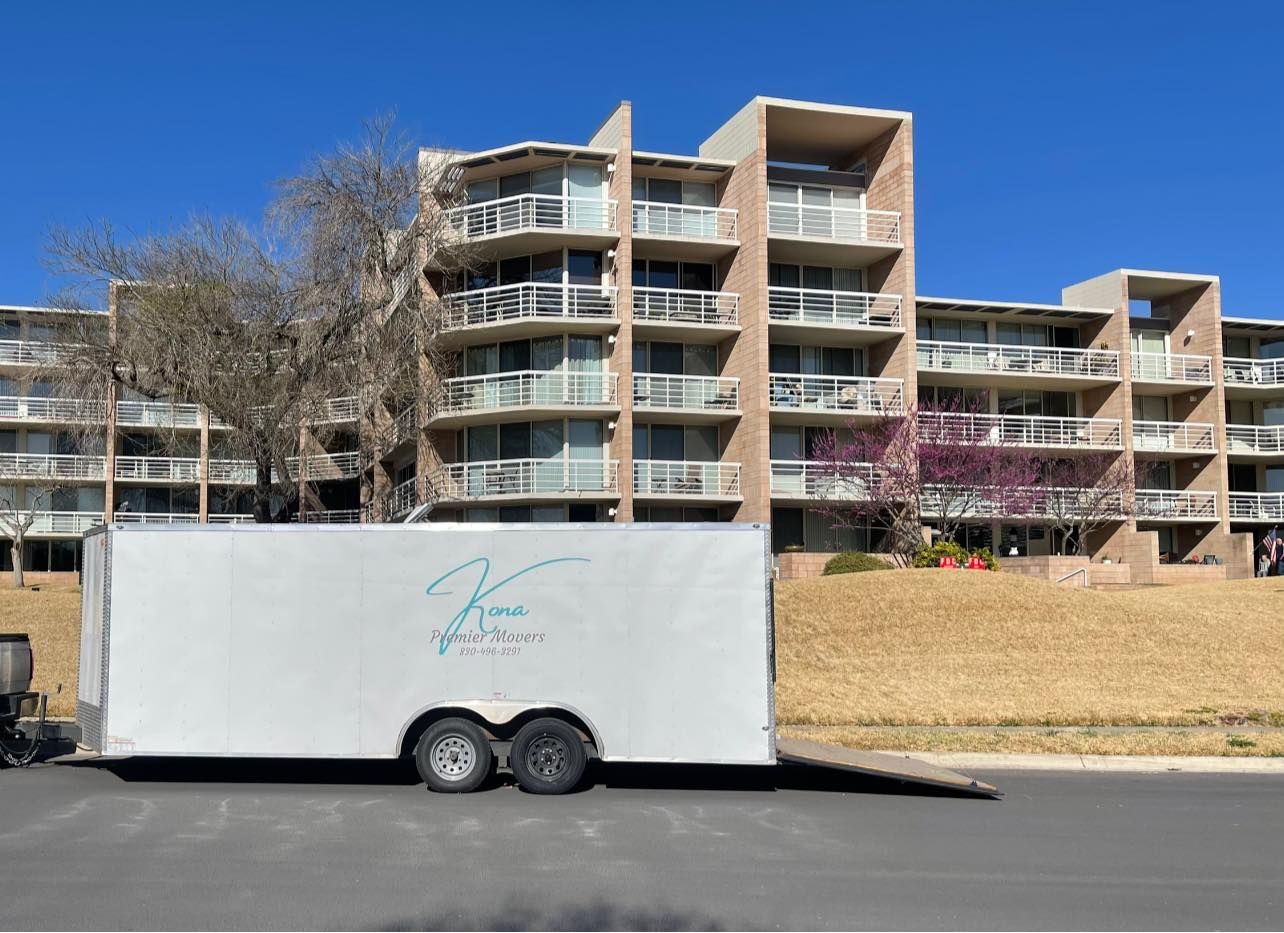 A white trailer is parked in front of a large apartment building.