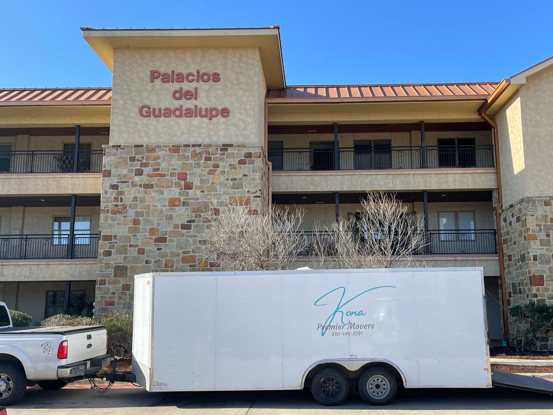 A white trailer is parked in front of a building that says palacios del guadalupe