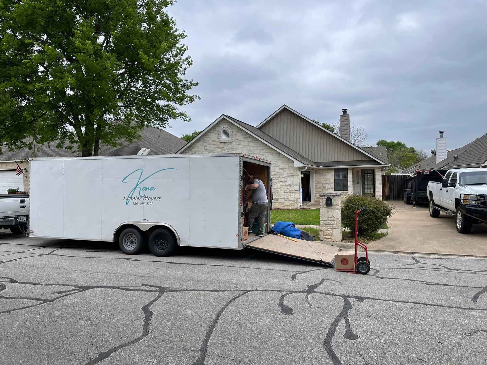 A white trailer is parked in front of a house.