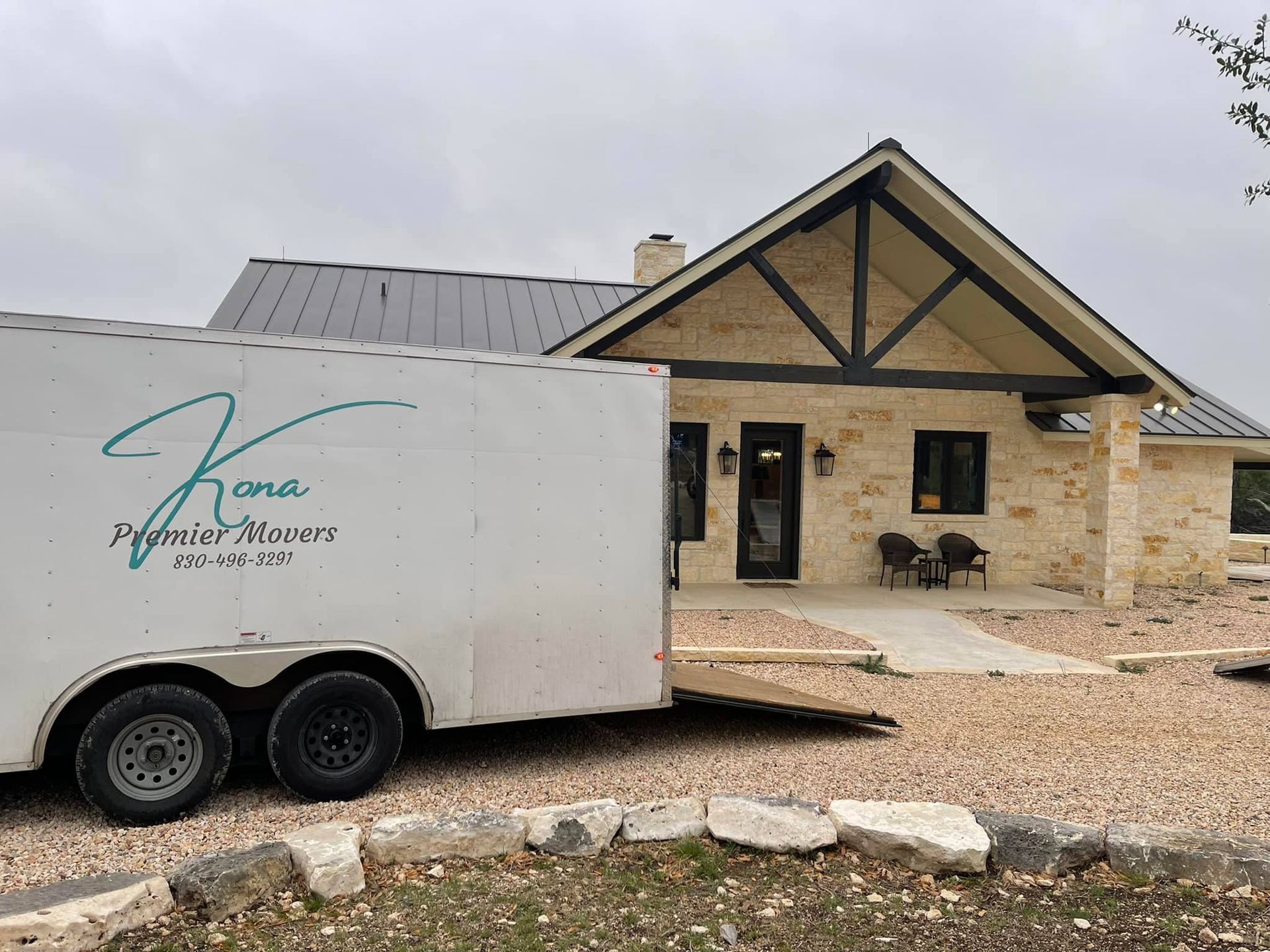 A white trailer is parked in front of a house.