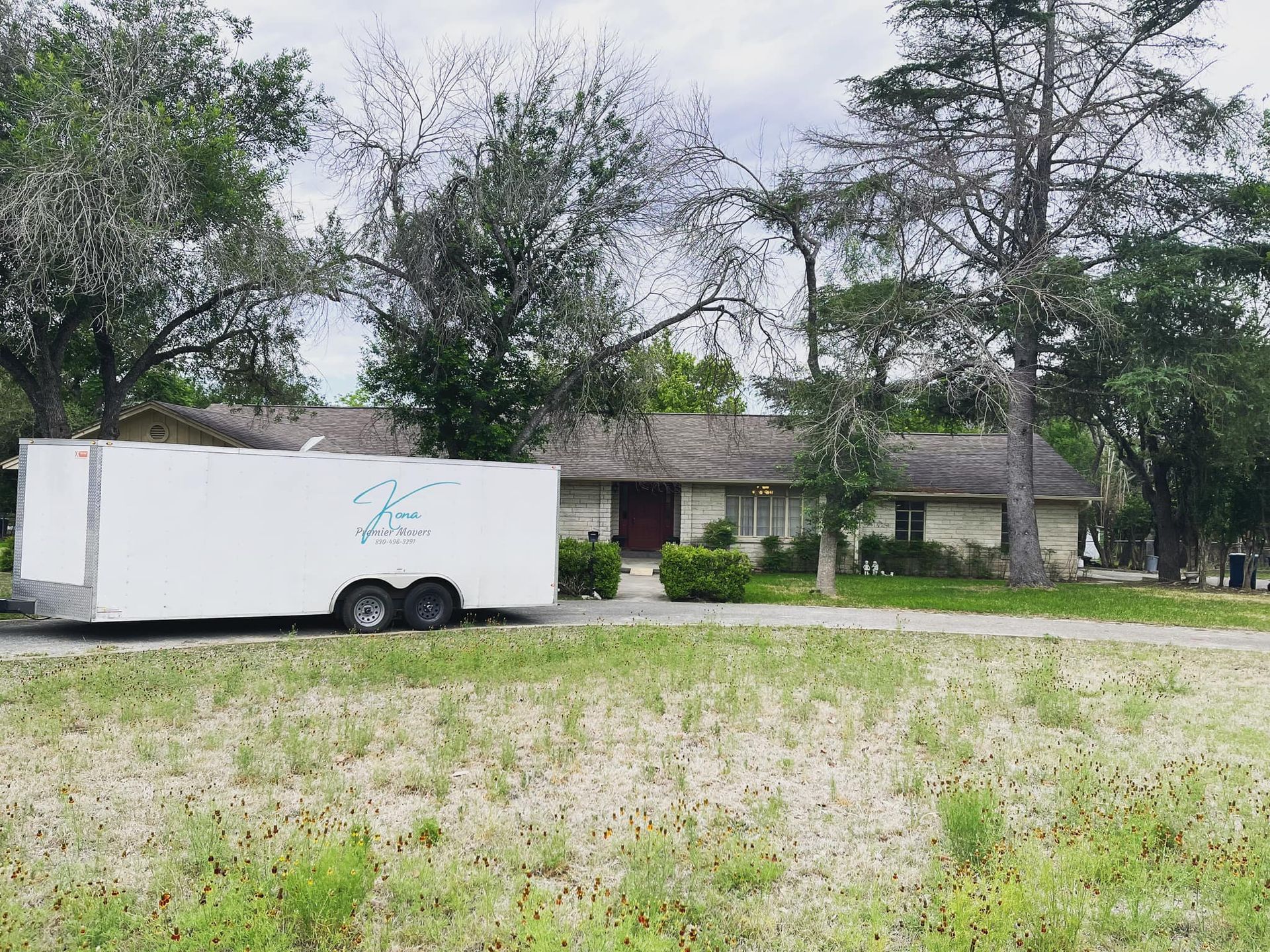 A white trailer is parked in front of a house.