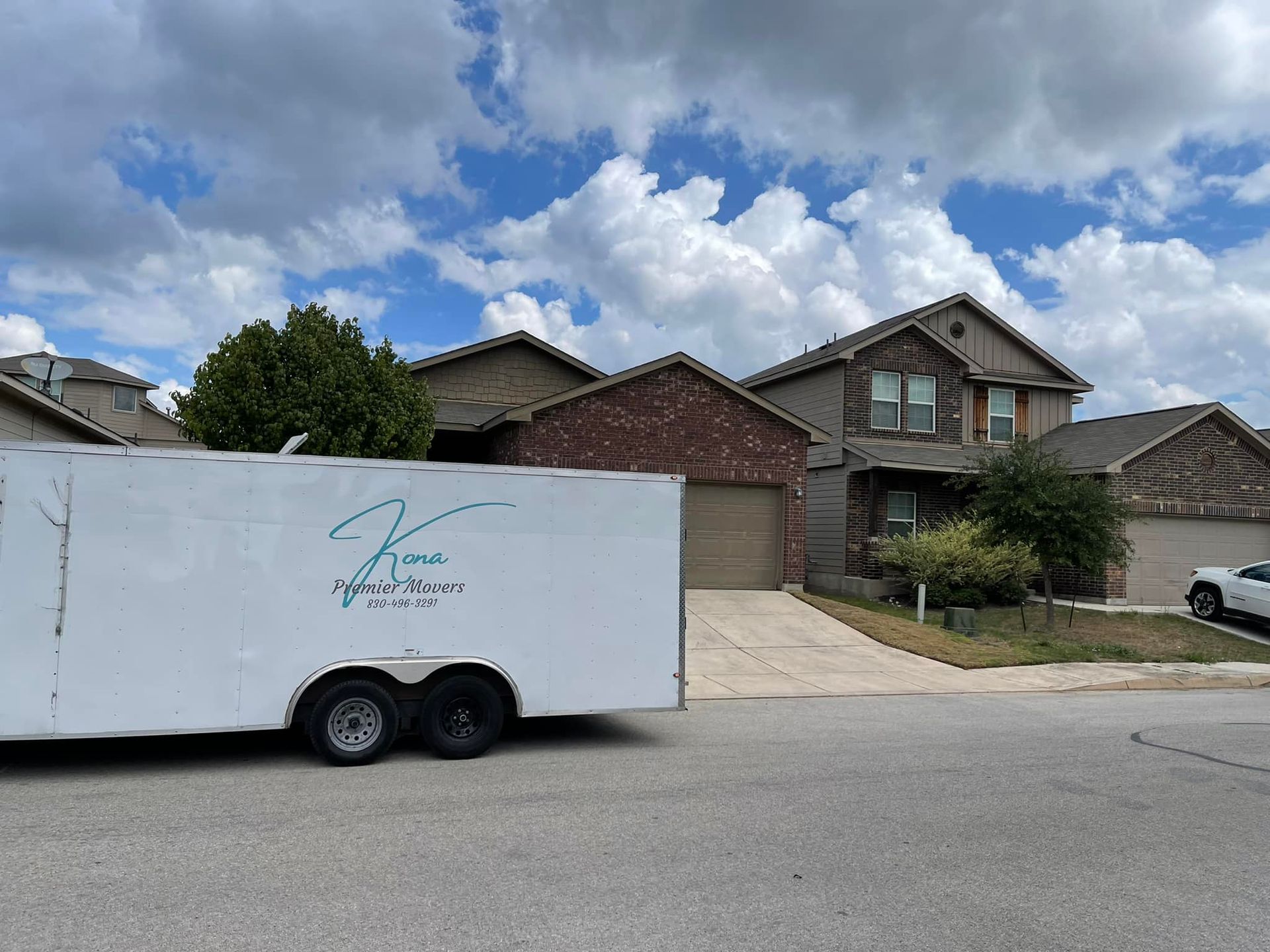 A white trailer is parked in front of a house.