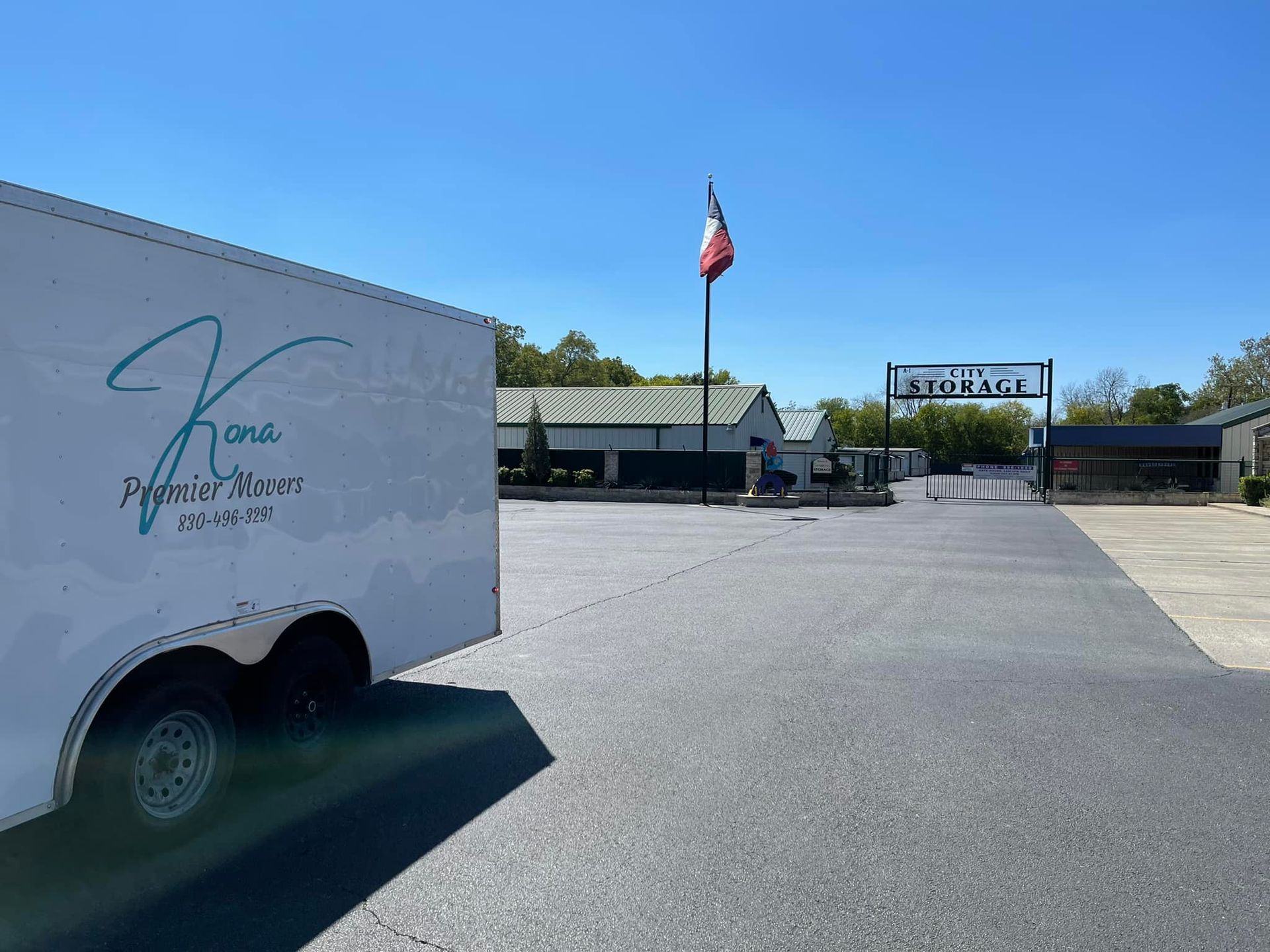 A white trailer is parked in front of a storage facility.