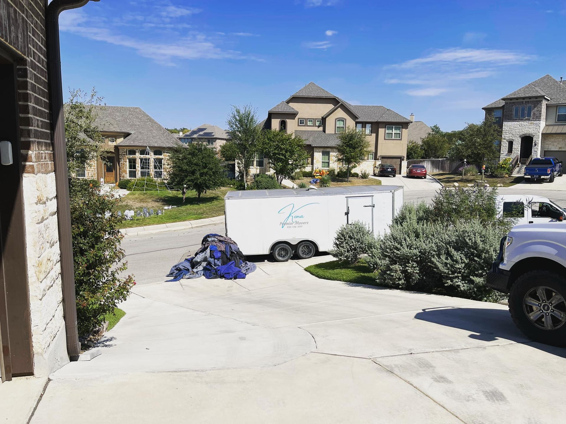 A white trailer is parked in a driveway next to a truck.