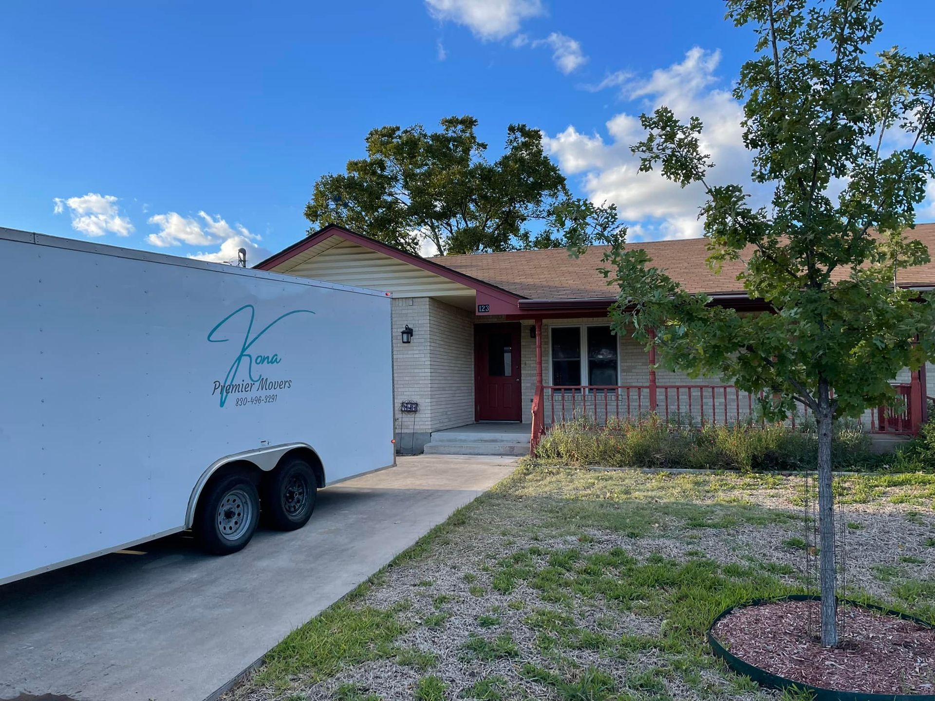 A white trailer is parked in front of a house.
