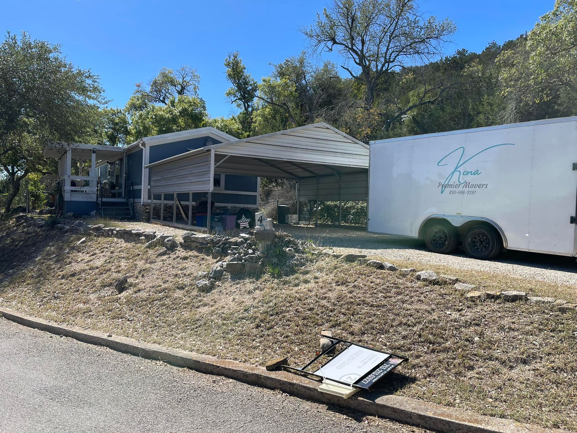 A white trailer is parked in front of a house.