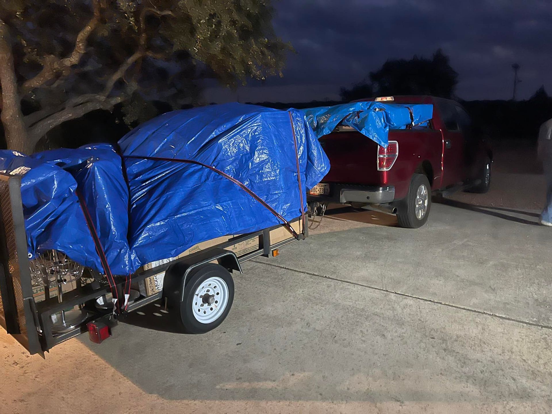 A red truck is pulling a trailer with a blue tarp on it