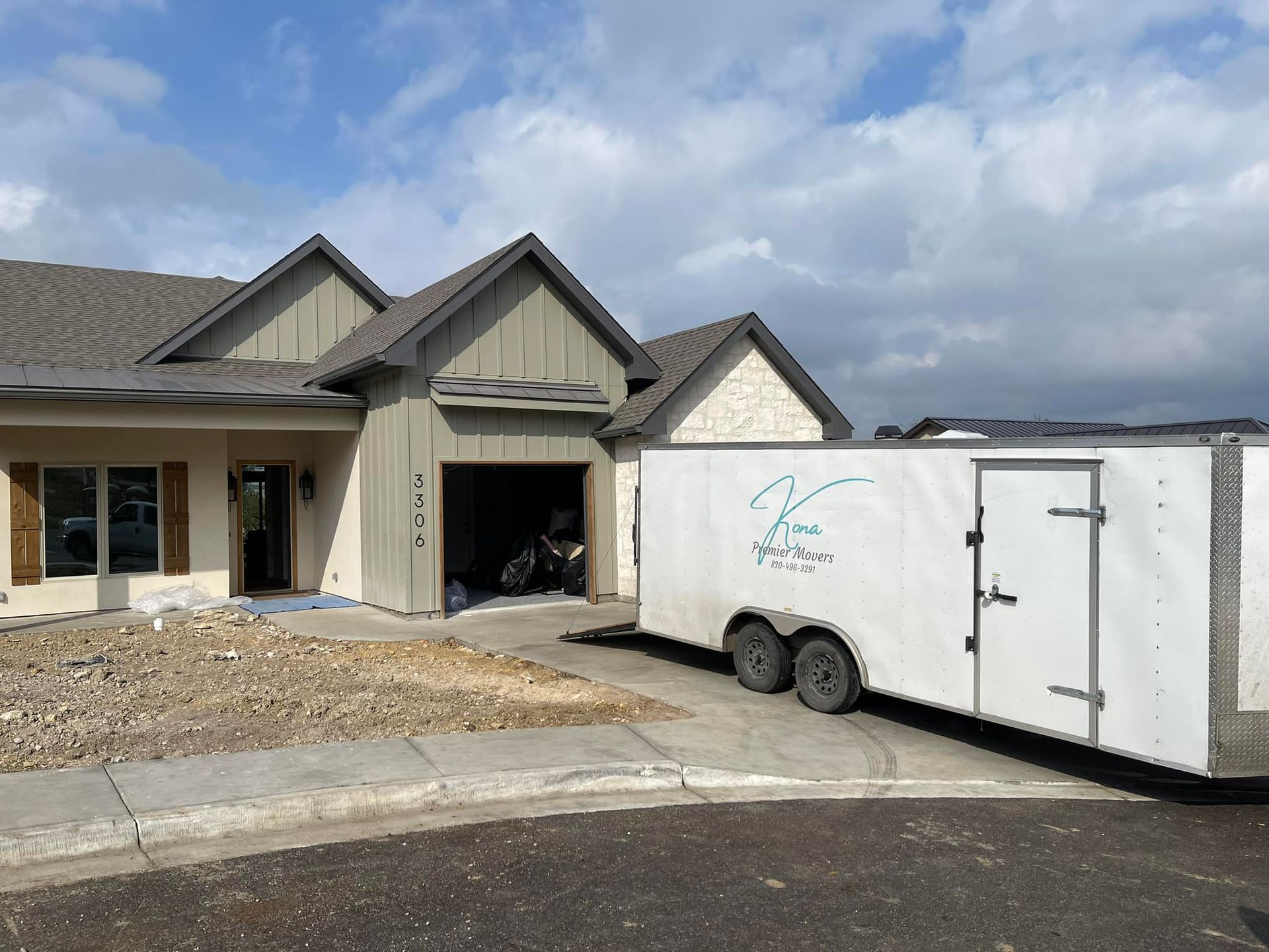 A white trailer is parked in front of a house.