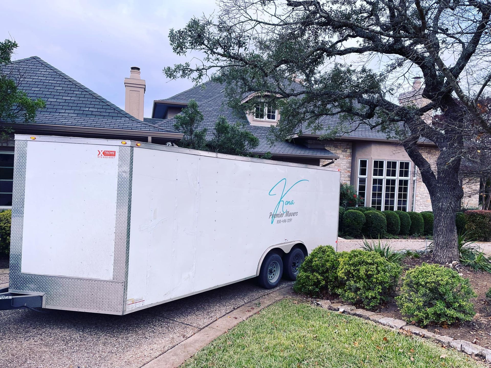 A white trailer is parked in front of a house.