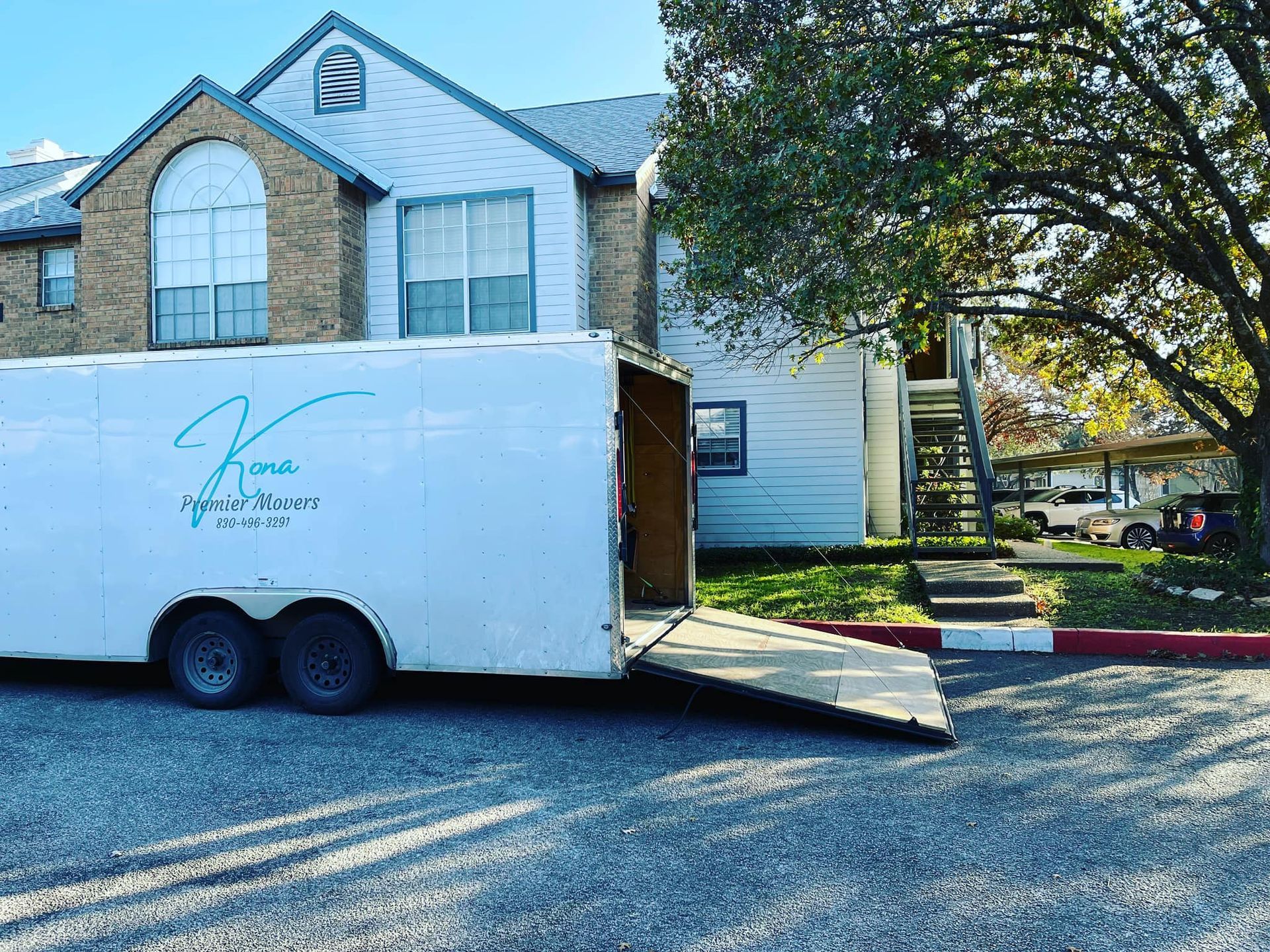 A white trailer is parked in front of a house.