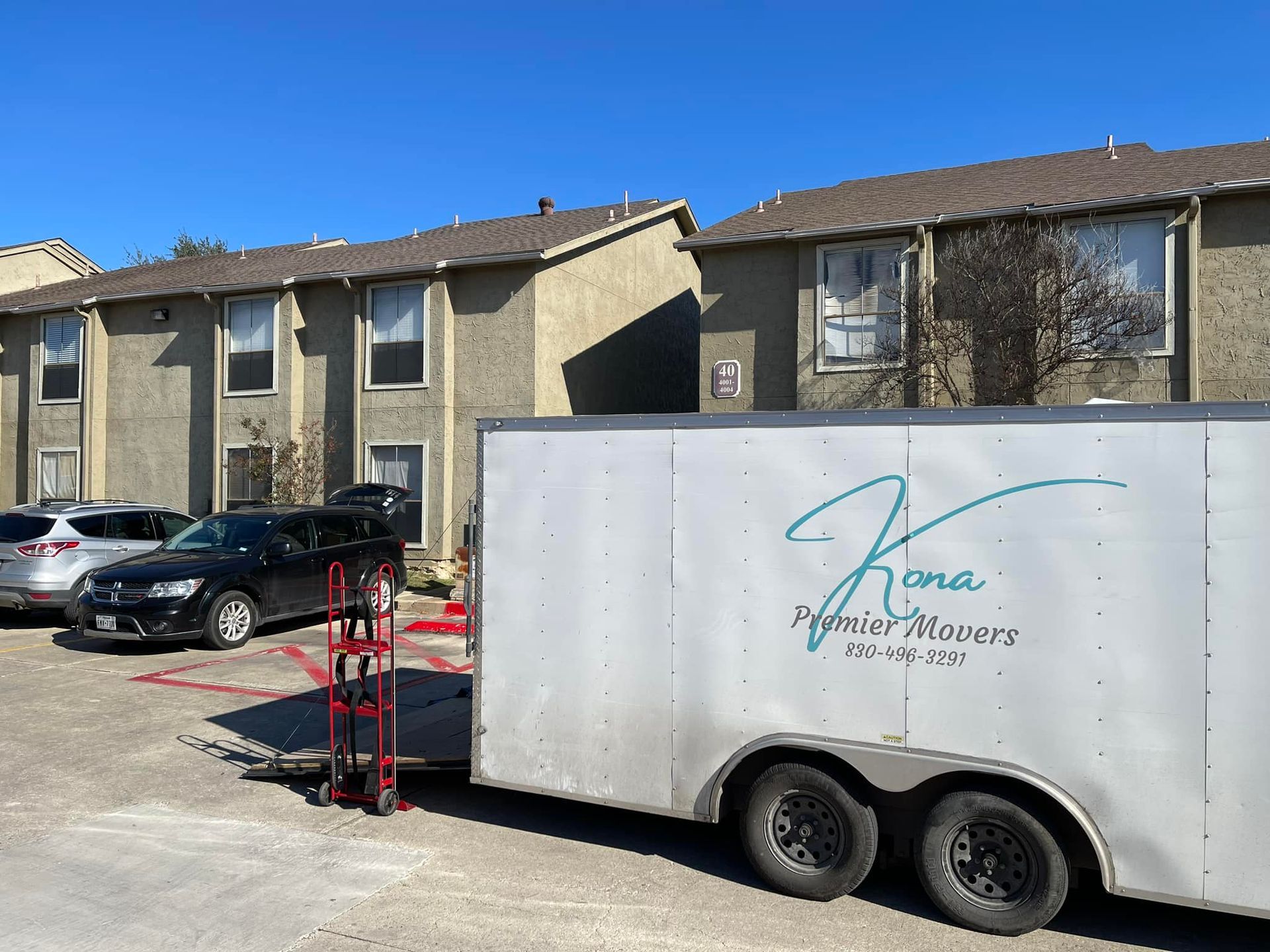 A white trailer is parked in a parking lot in front of a building.