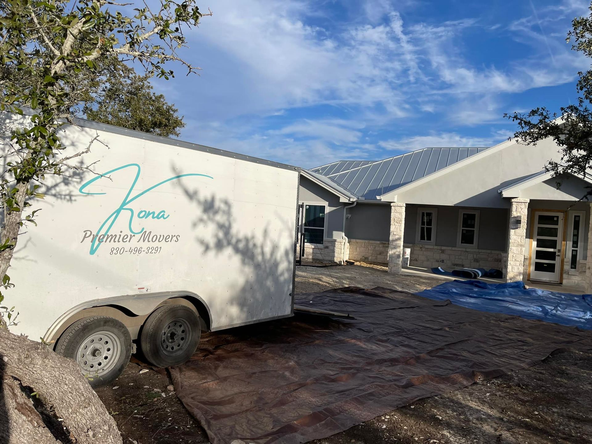 A white trailer is parked in front of a house.