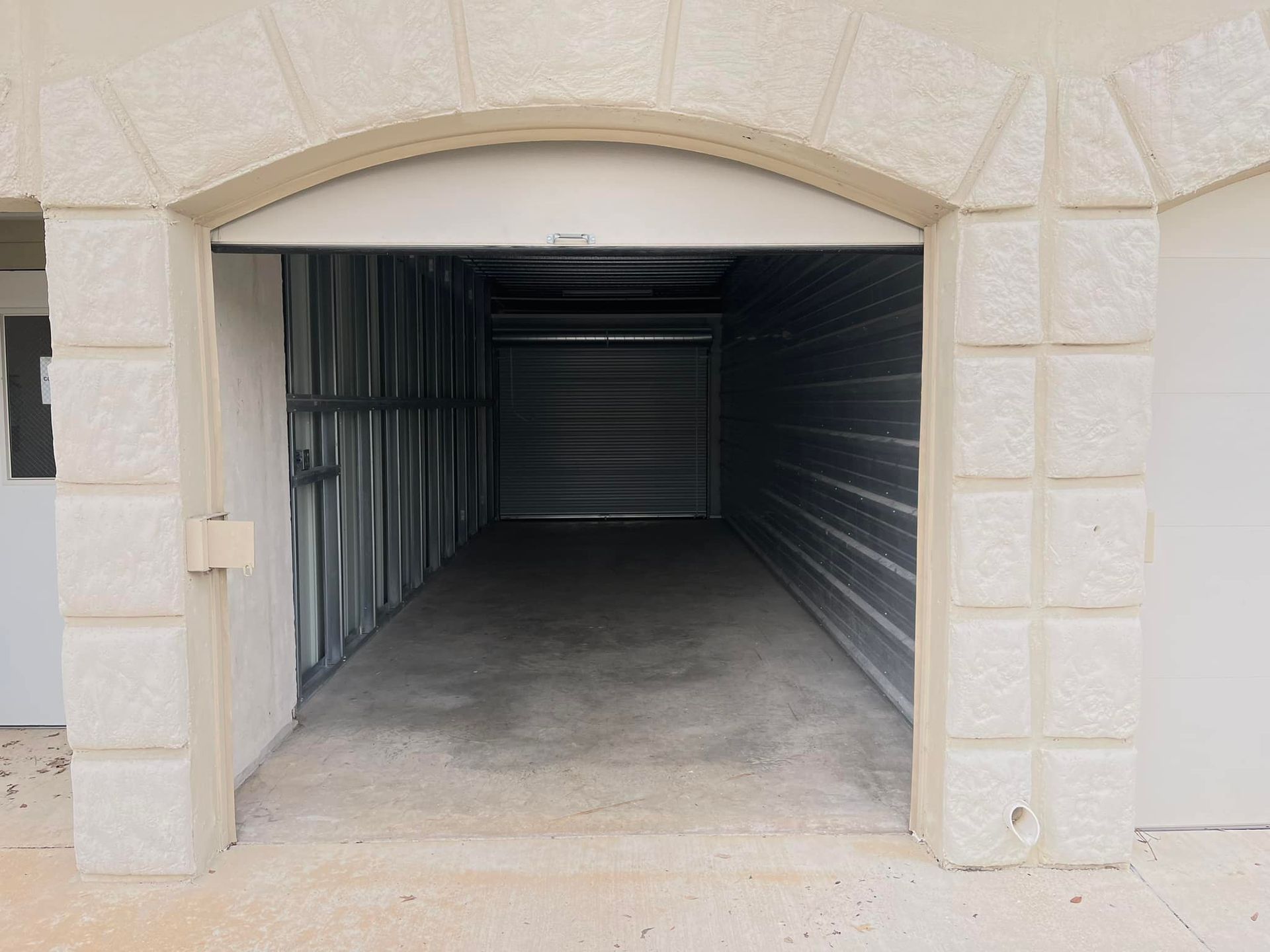 An empty garage with the door open and a brick wall.