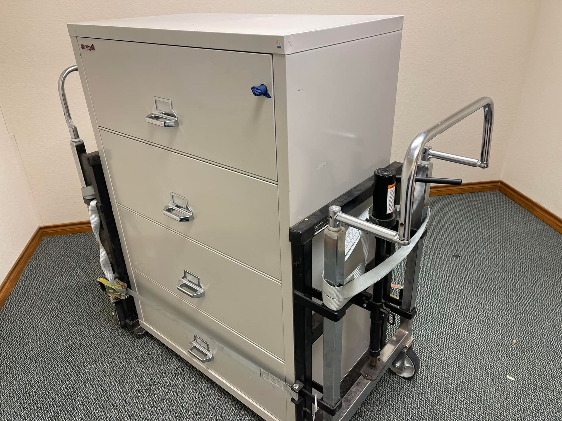 A filing cabinet is being moved by a dolly in a room.