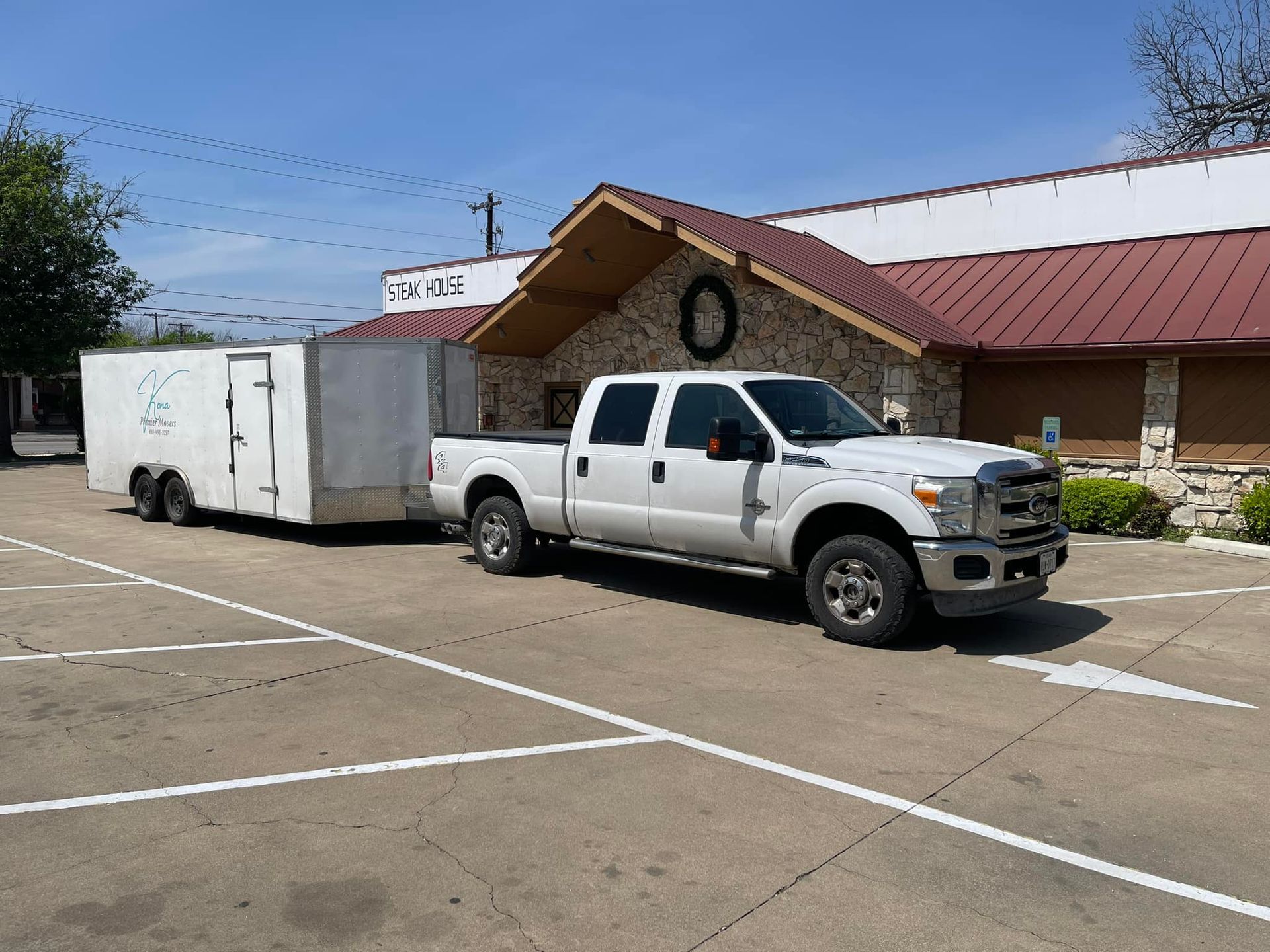 A white truck with a trailer attached to it is parked in a parking lot.