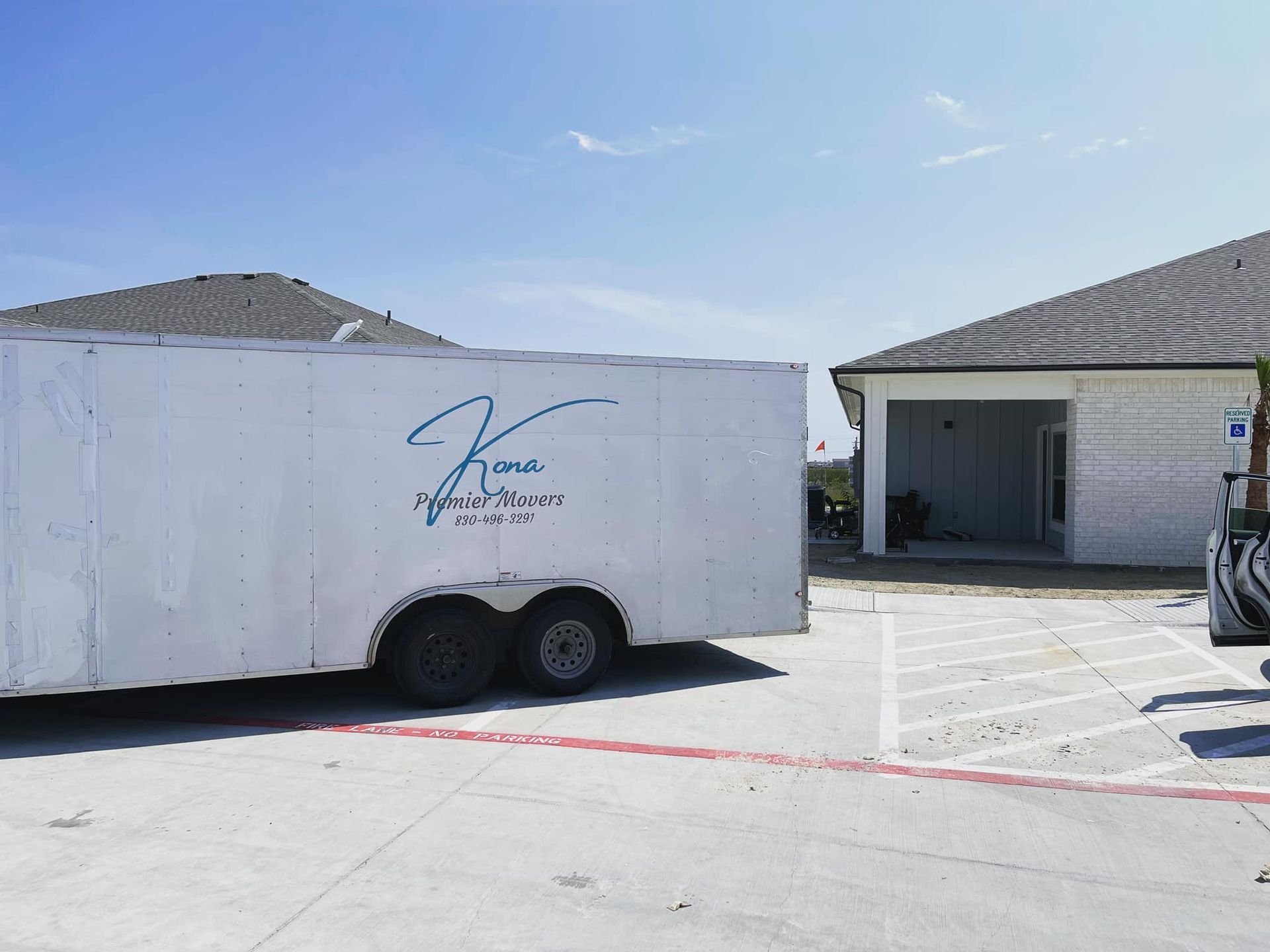 A white trailer is parked in front of a house.