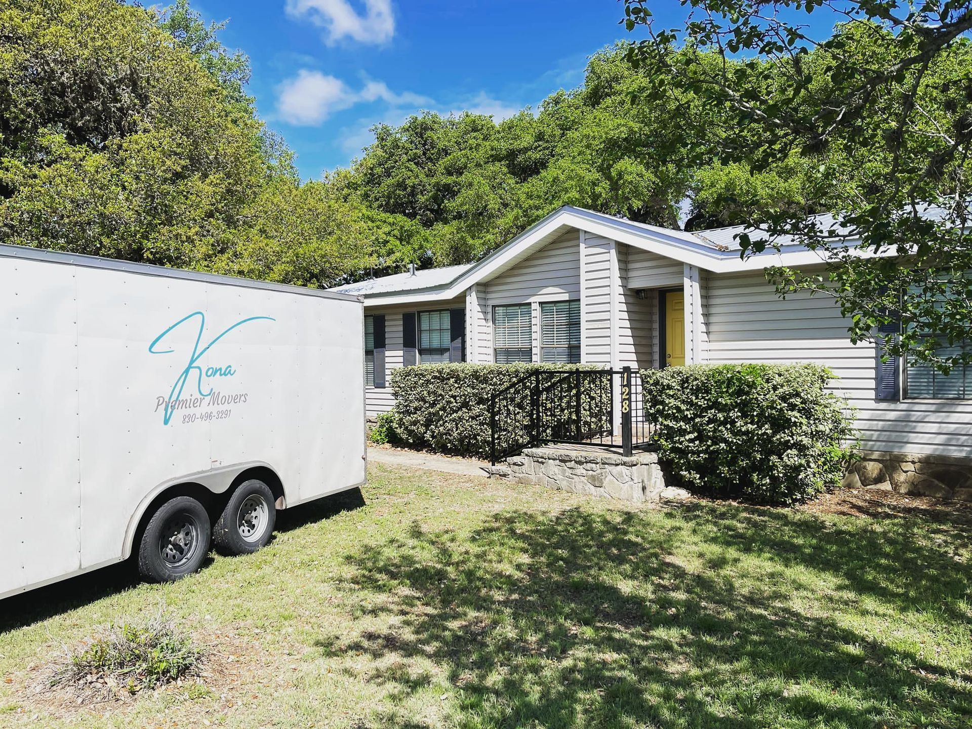 A white trailer is parked in front of a house.