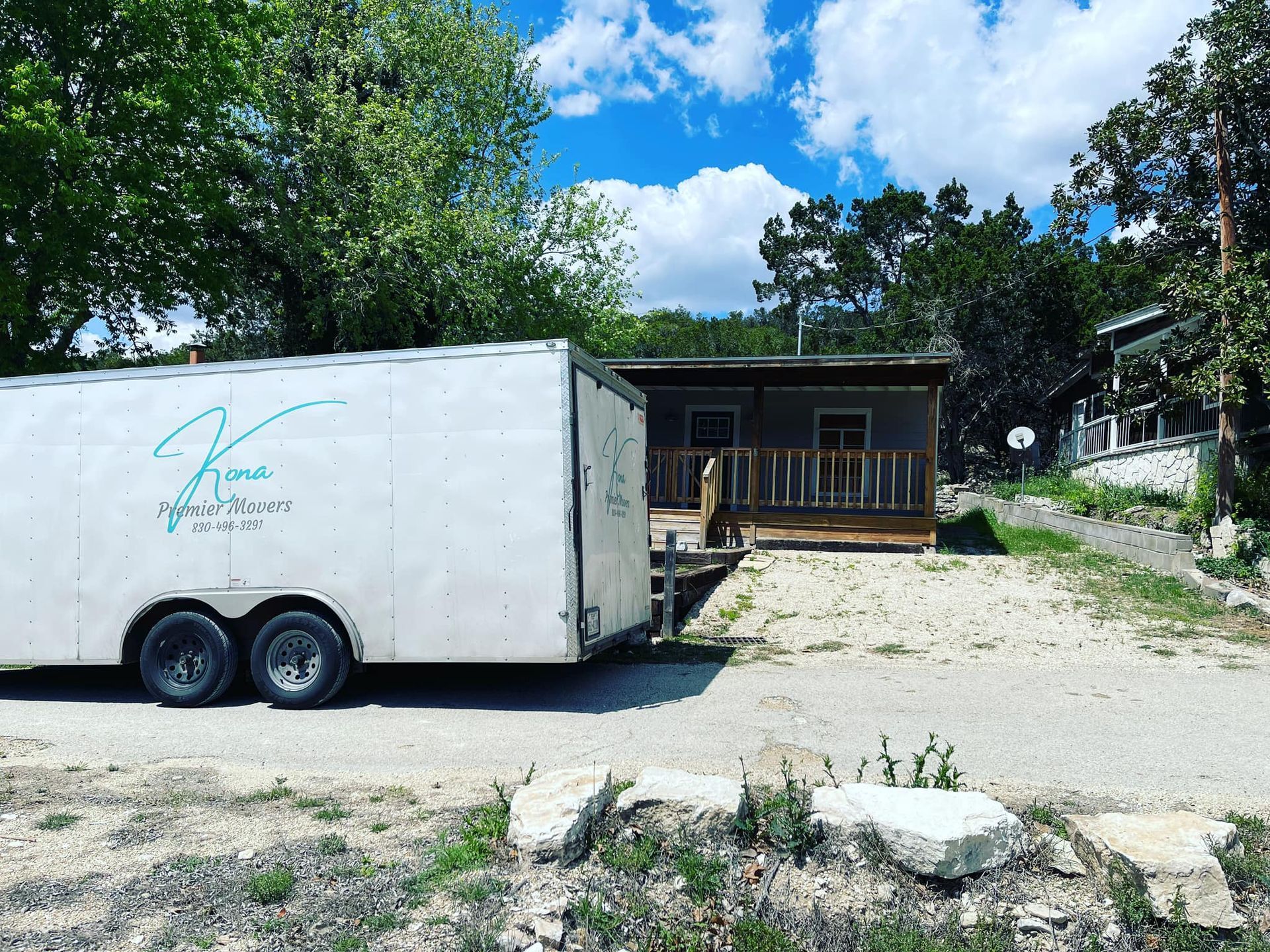 A white trailer is parked in front of a house.