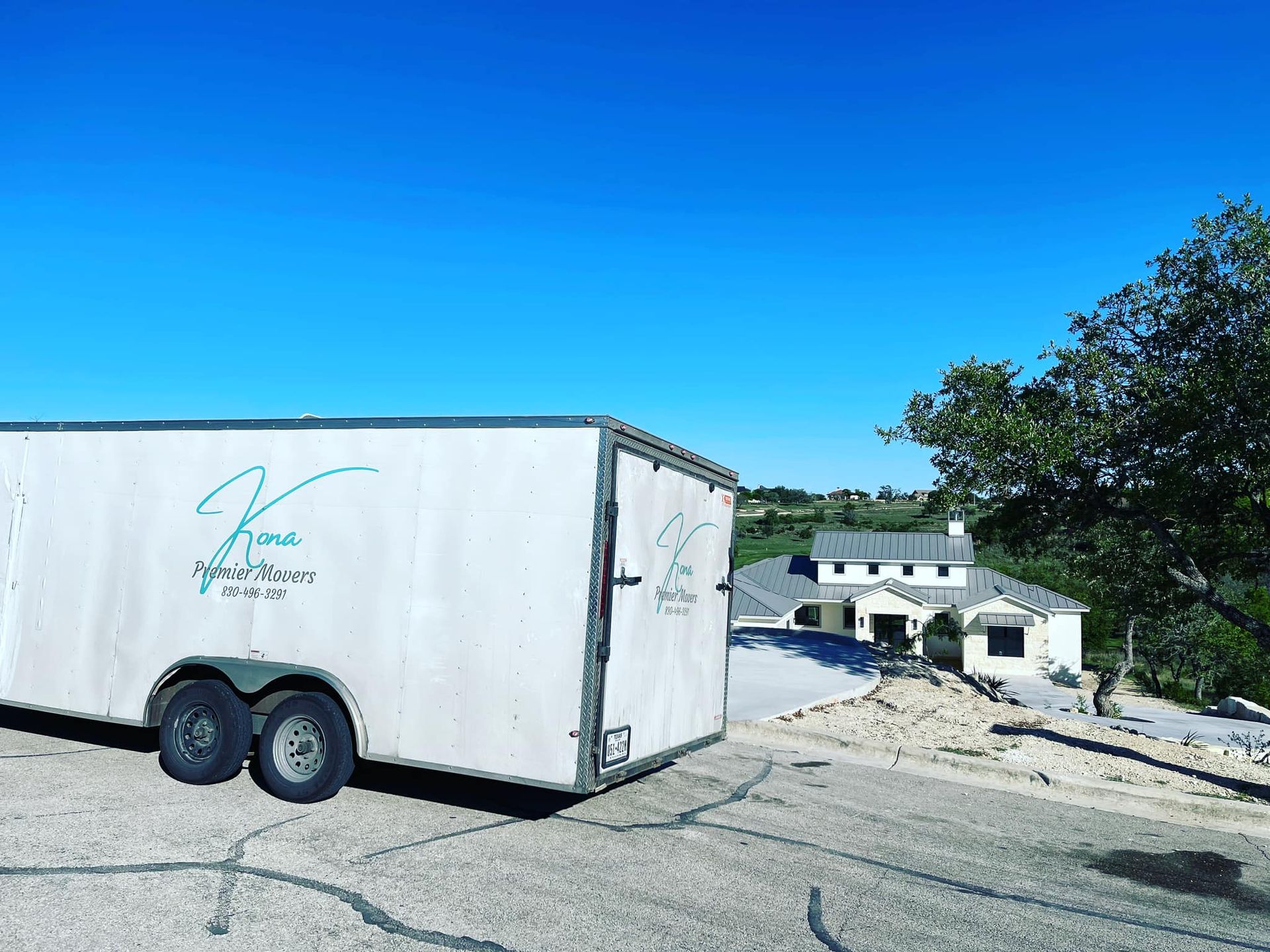 A white trailer is parked on the side of the road in front of a house.
