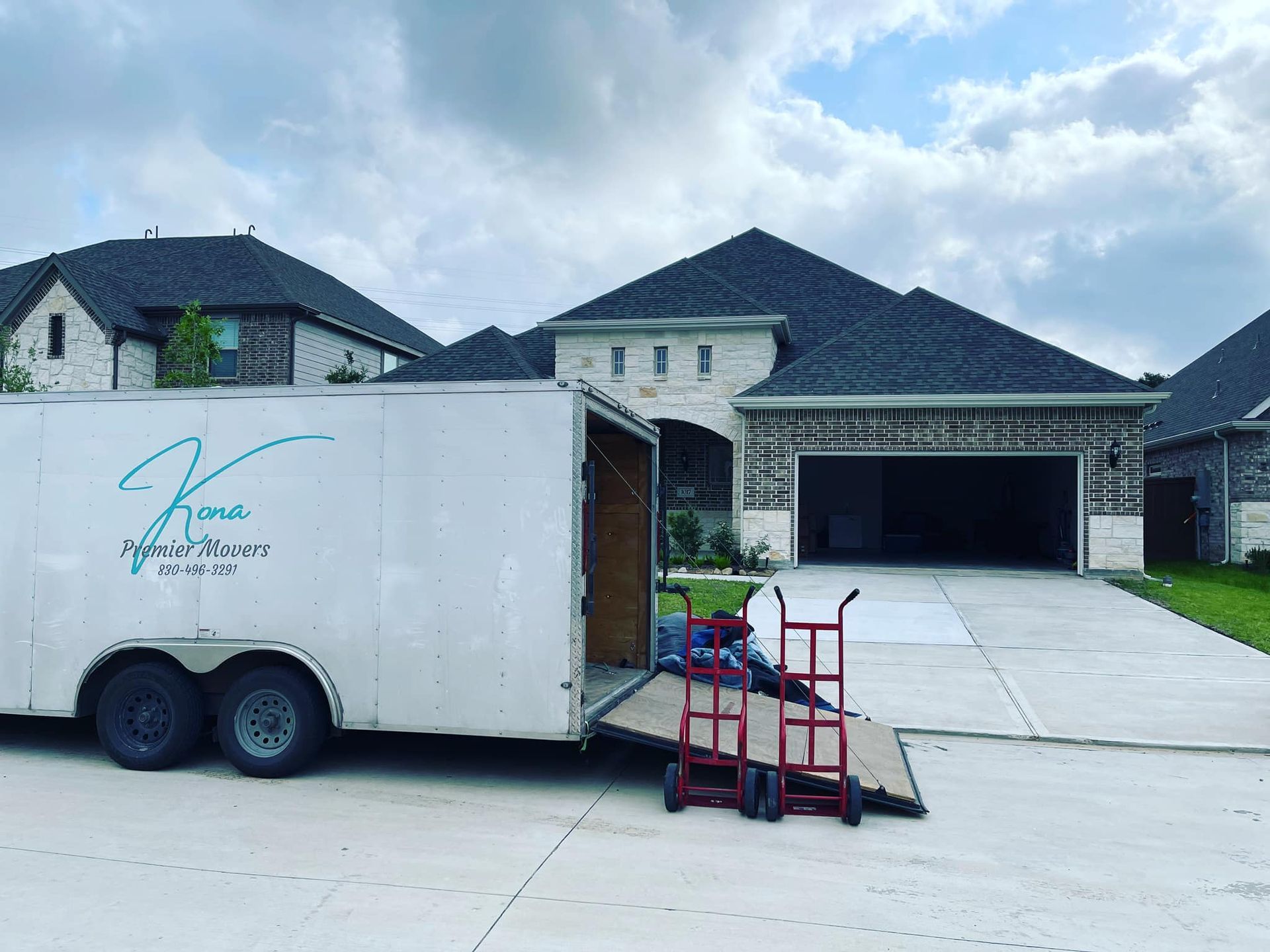 A white trailer is parked in front of a house.