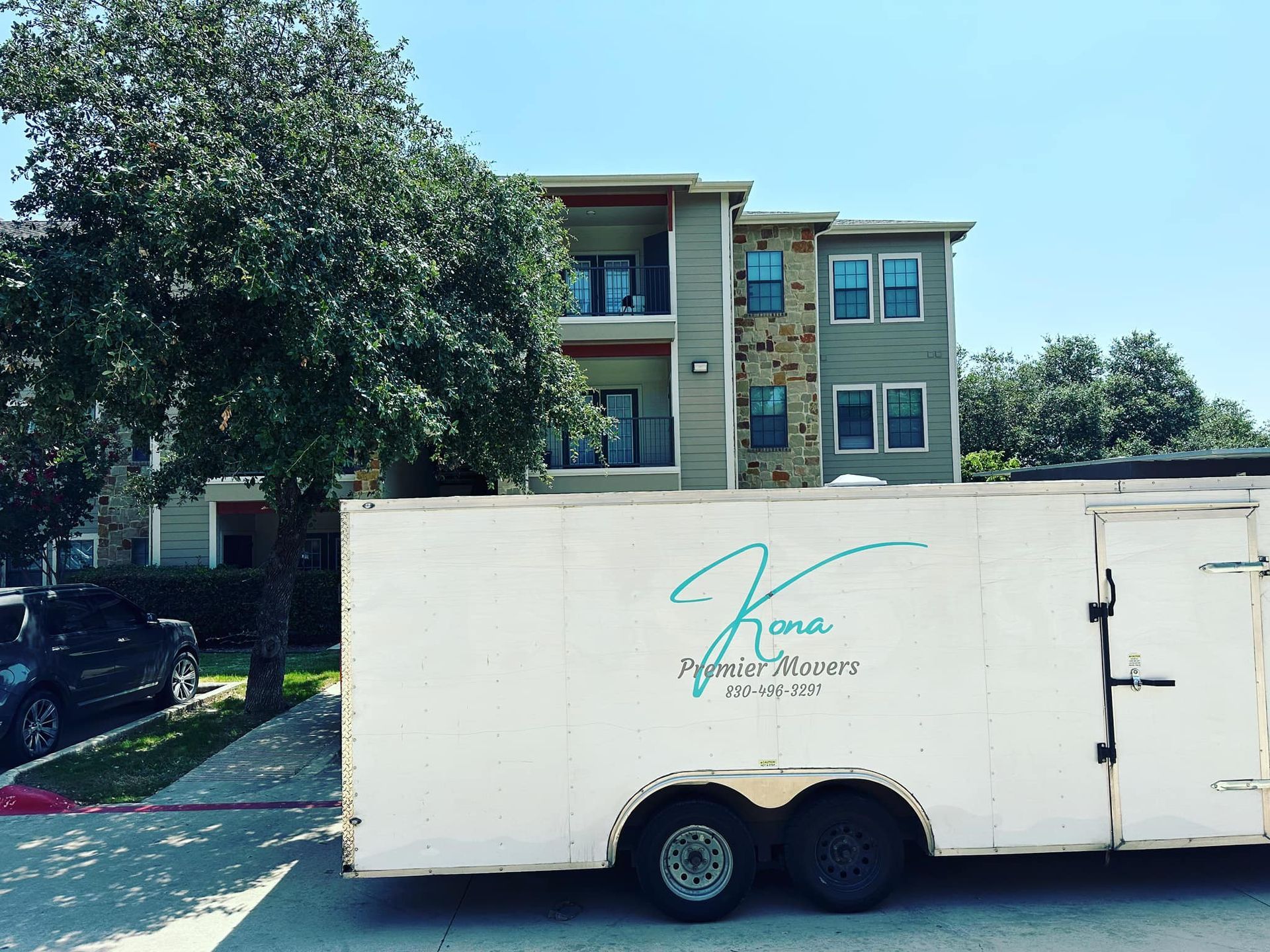 A white trailer is parked in front of a building