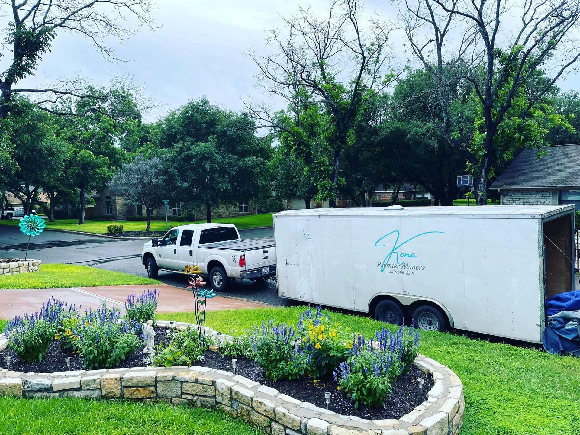 A white trailer is parked in a yard next to a truck.