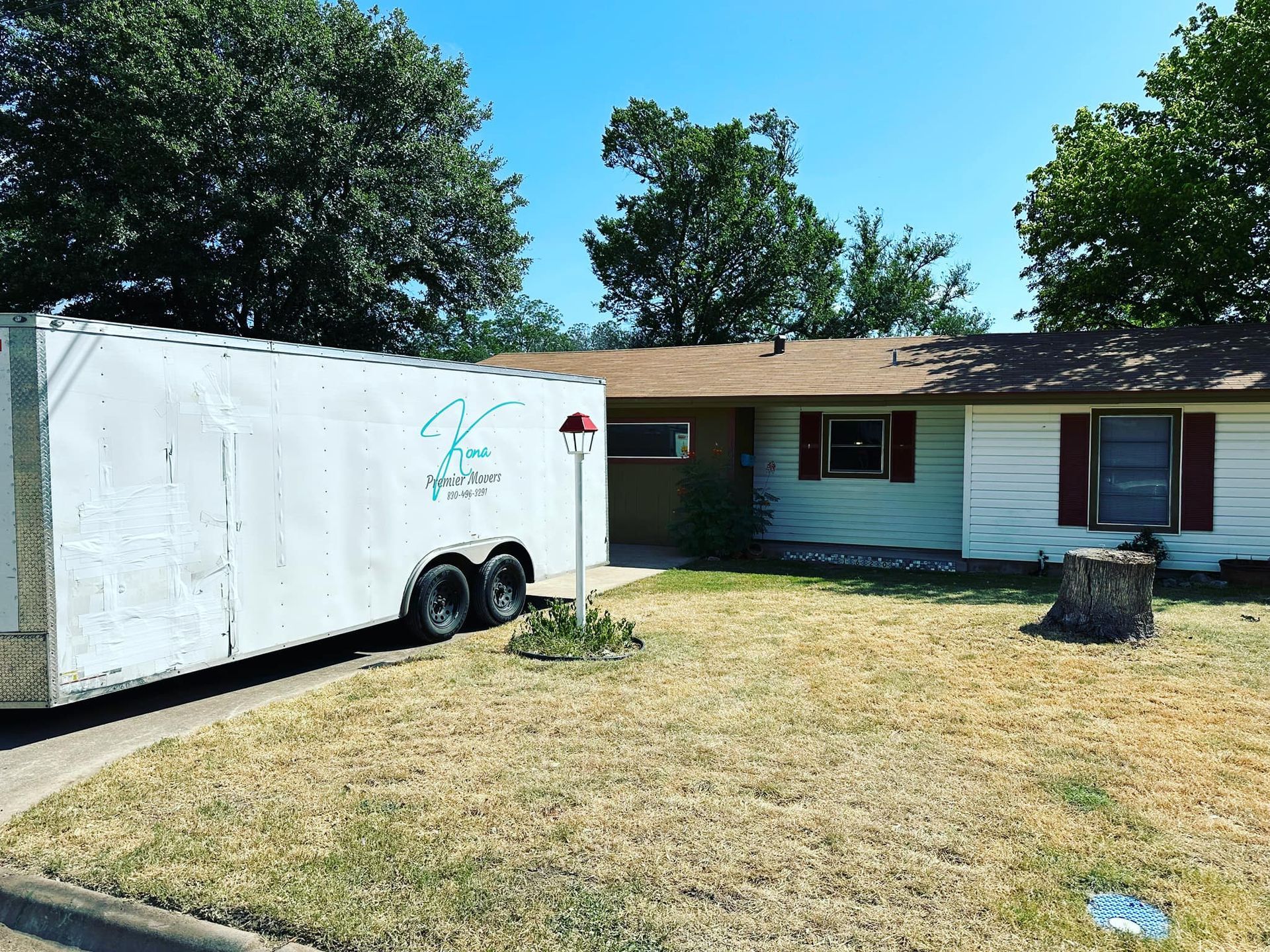 A white trailer is parked in front of a house.