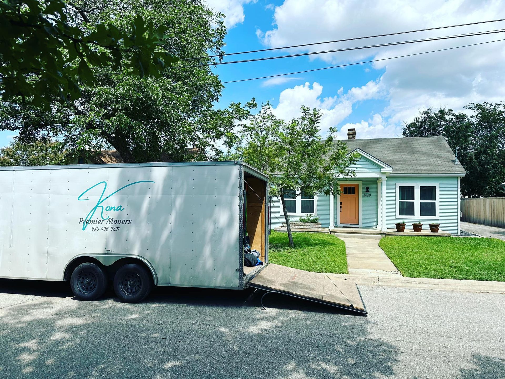 A white trailer is parked in front of a house.