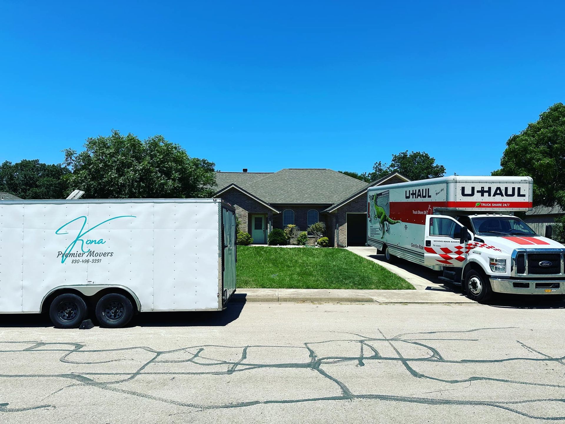 Two u-haul trucks are parked in front of a house.