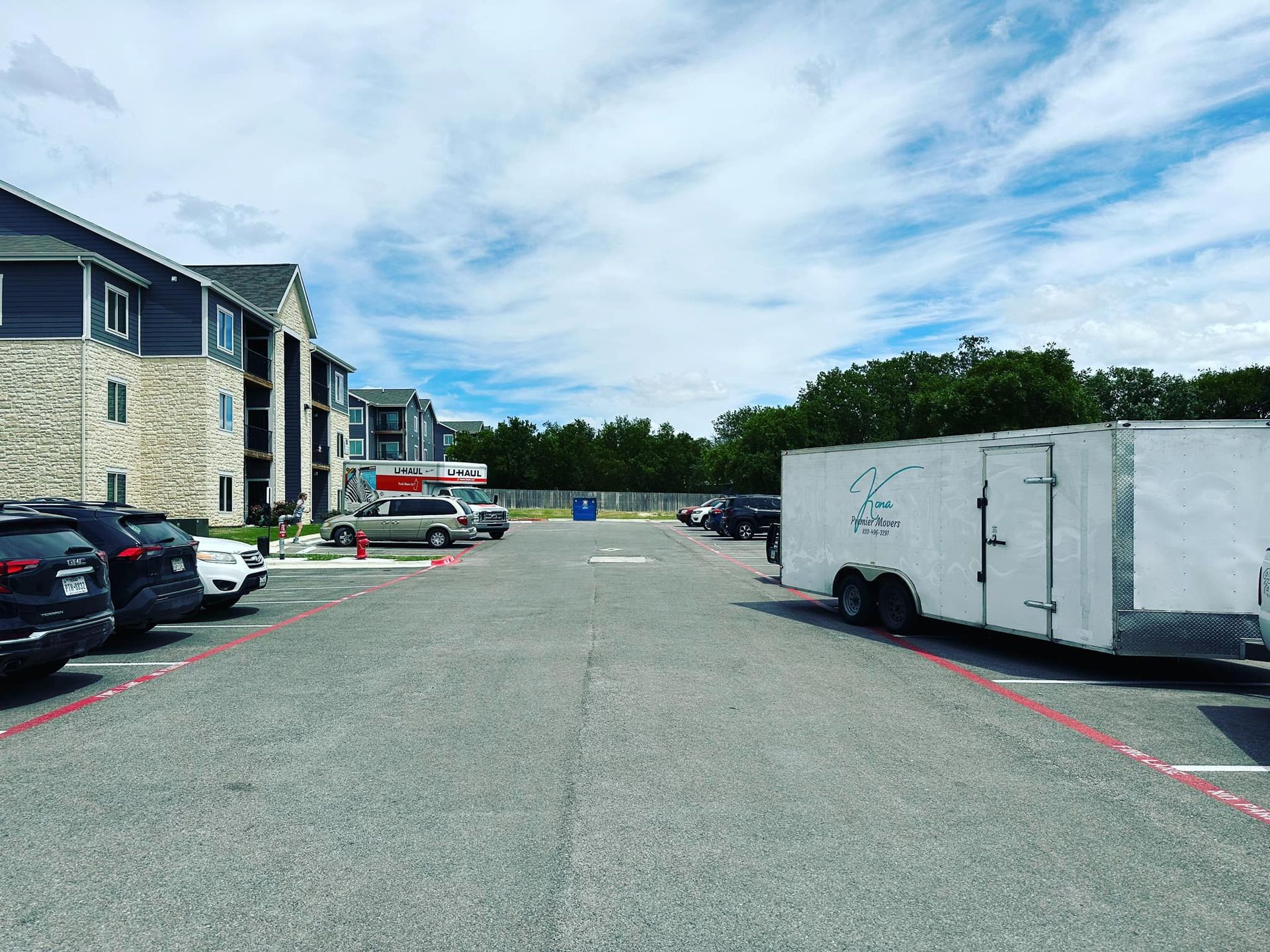 A white trailer is parked in a parking lot in front of a building.