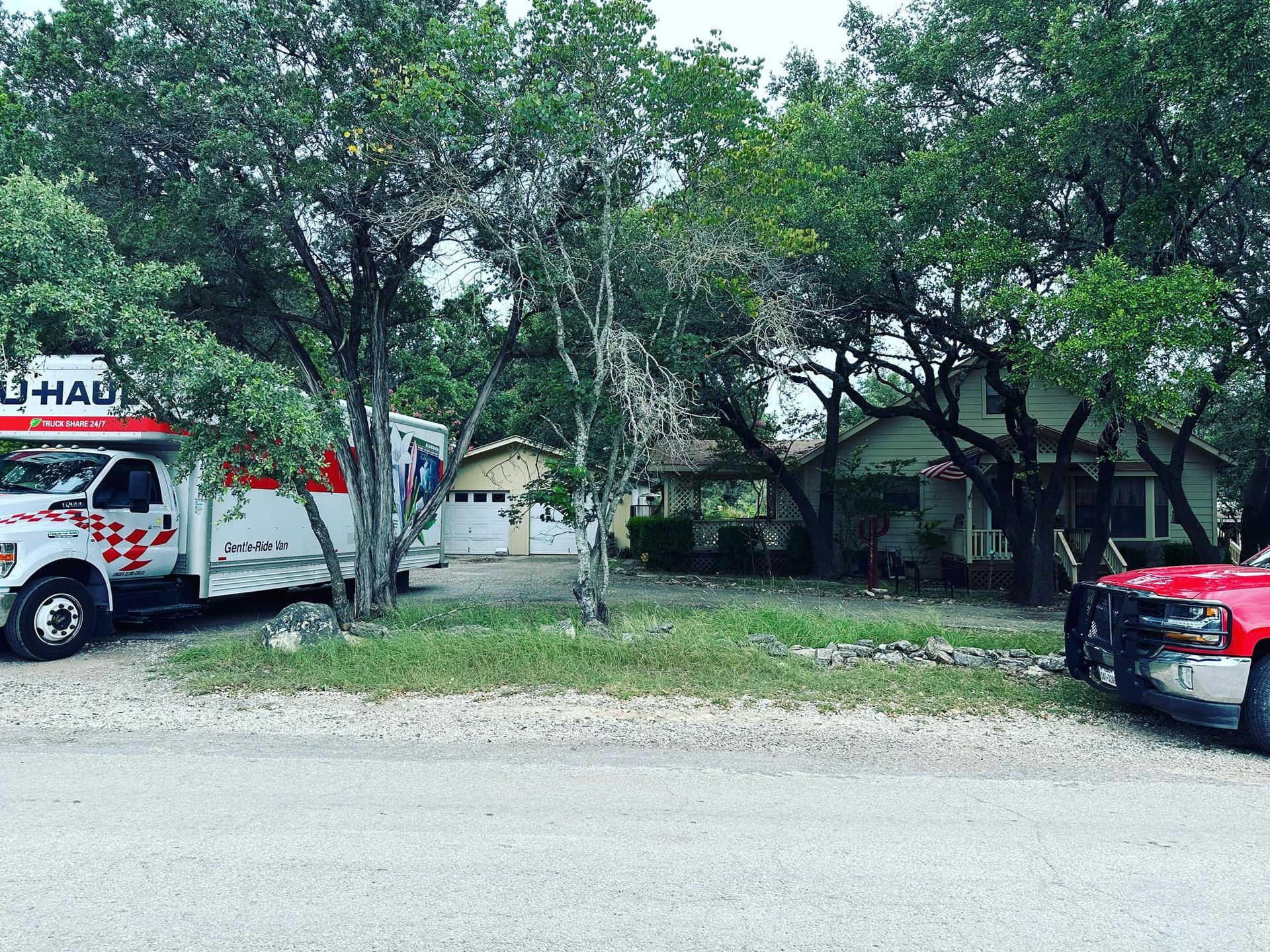 Two u-haul trucks are parked in front of a house.